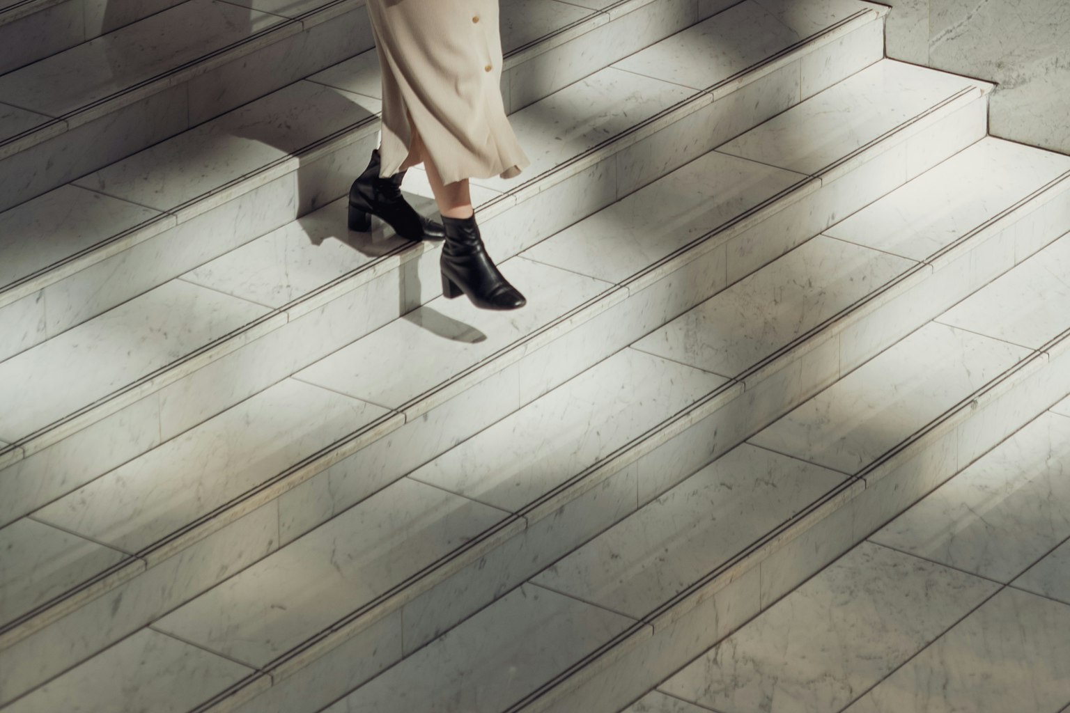 A woman's feet descending stairs with contrasting shadows