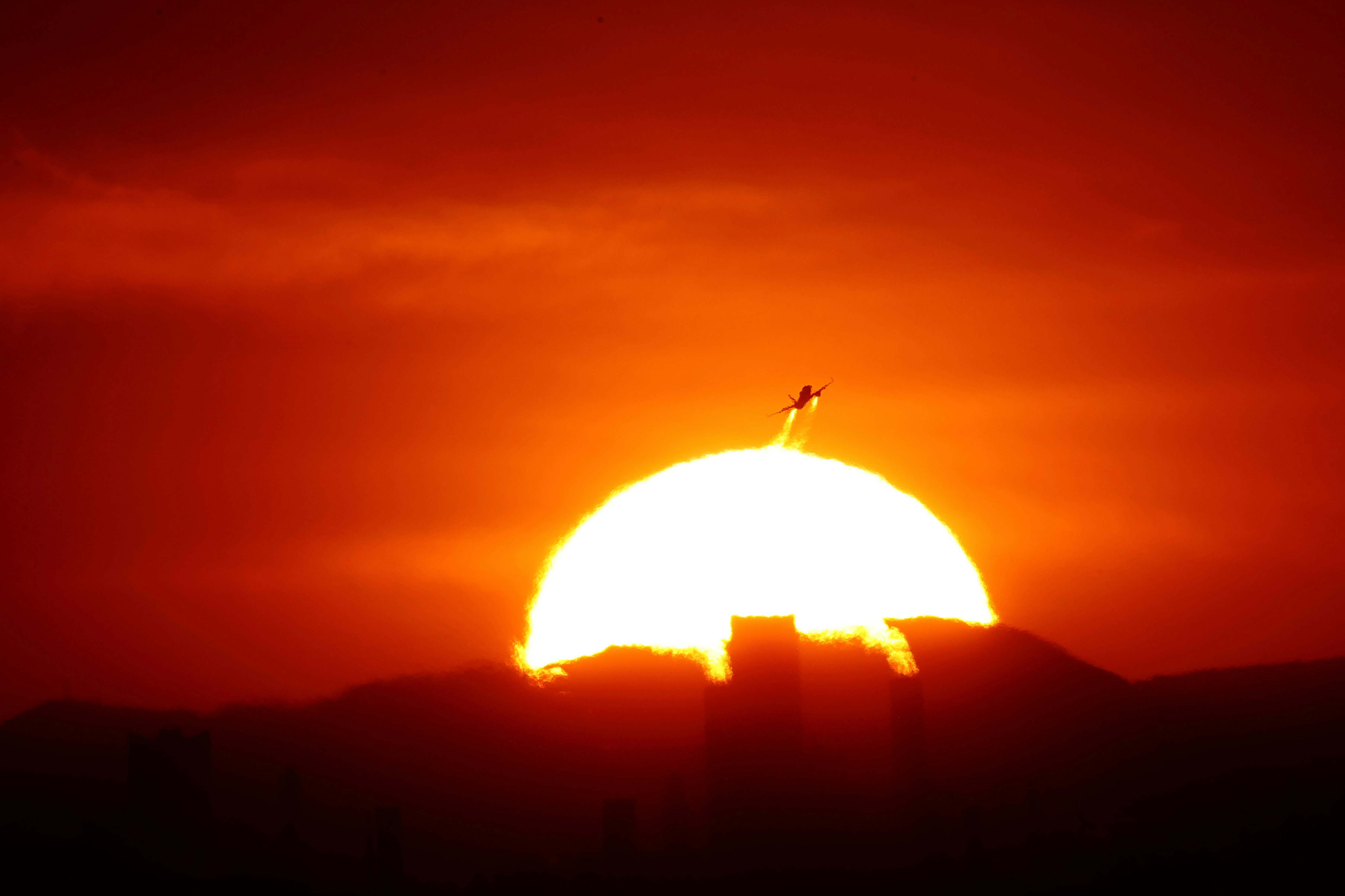 夕焼けの空に浮かぶ飛行機の離陸シルエット