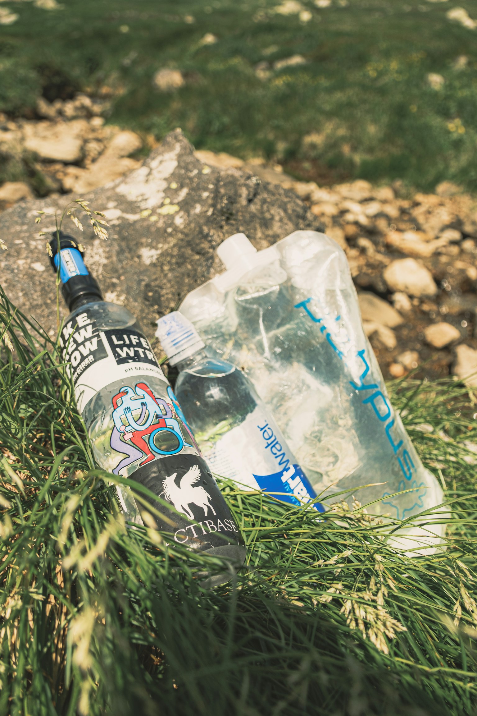 A water bottle and hydration pack resting on green grass