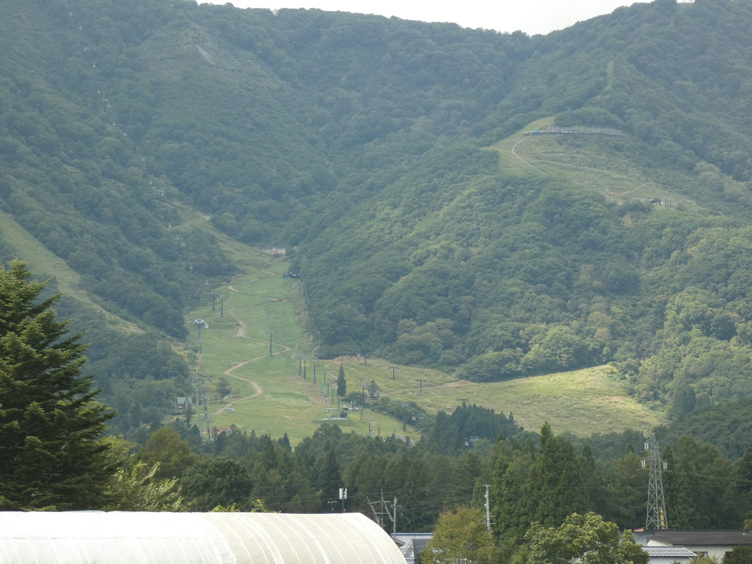 Paesaggio montano verdeggiante con resti di pista da sci