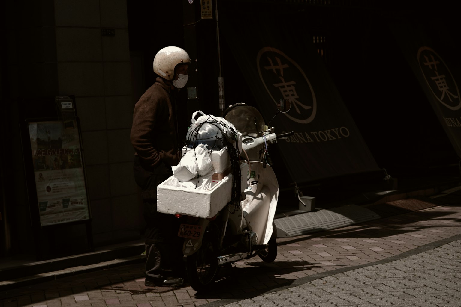 一個人在城市街道上推著載貨的摩托車