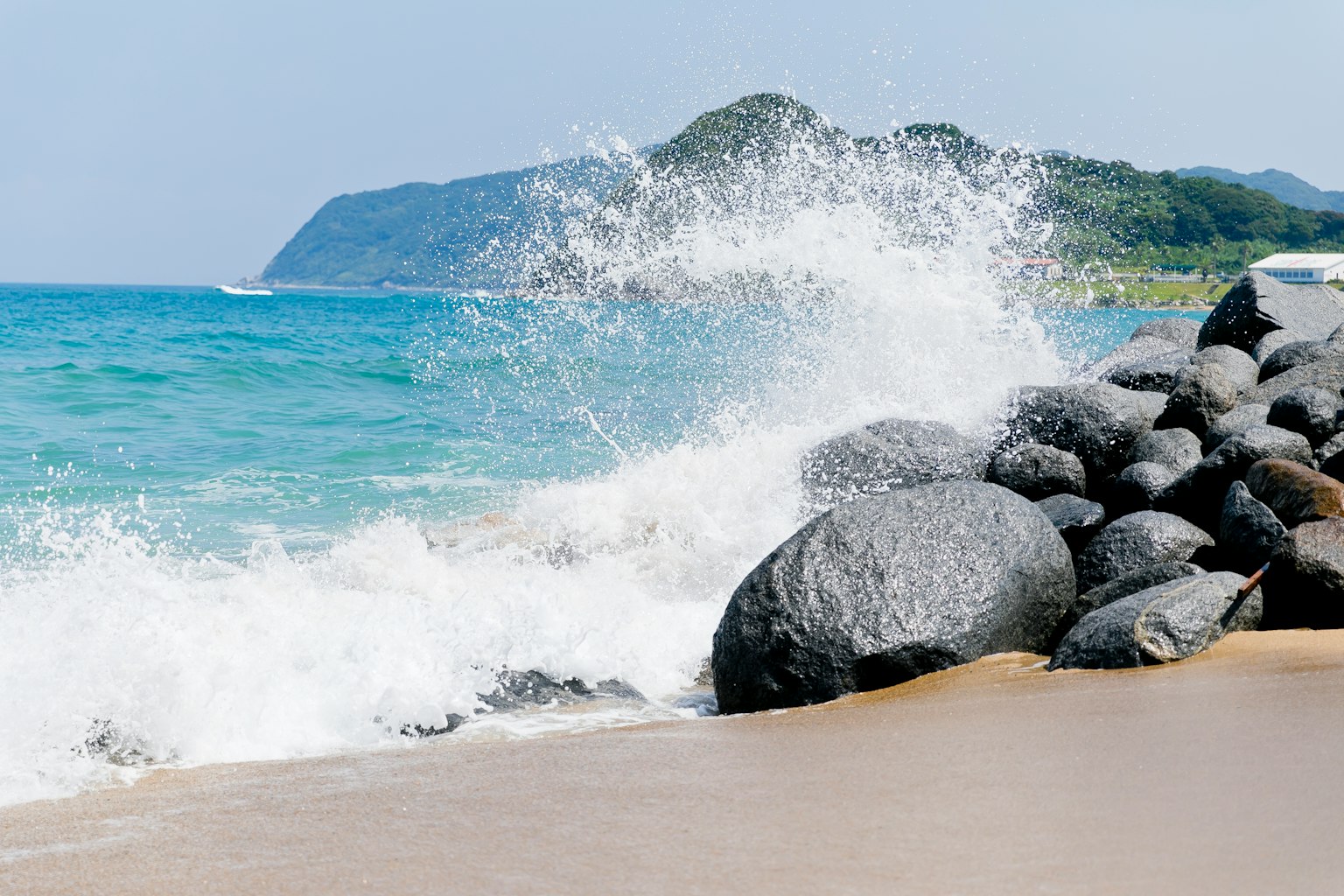 Pemandangan pantai dengan ombak menghantam batu