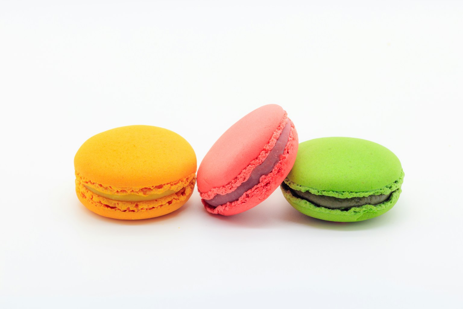 Colorful macarons arranged in a row featuring yellow, pink, and green colors