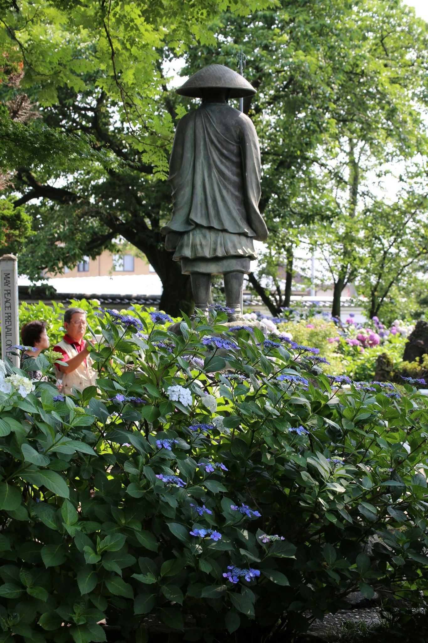 花壇の前に立つ銅像と緑の木々