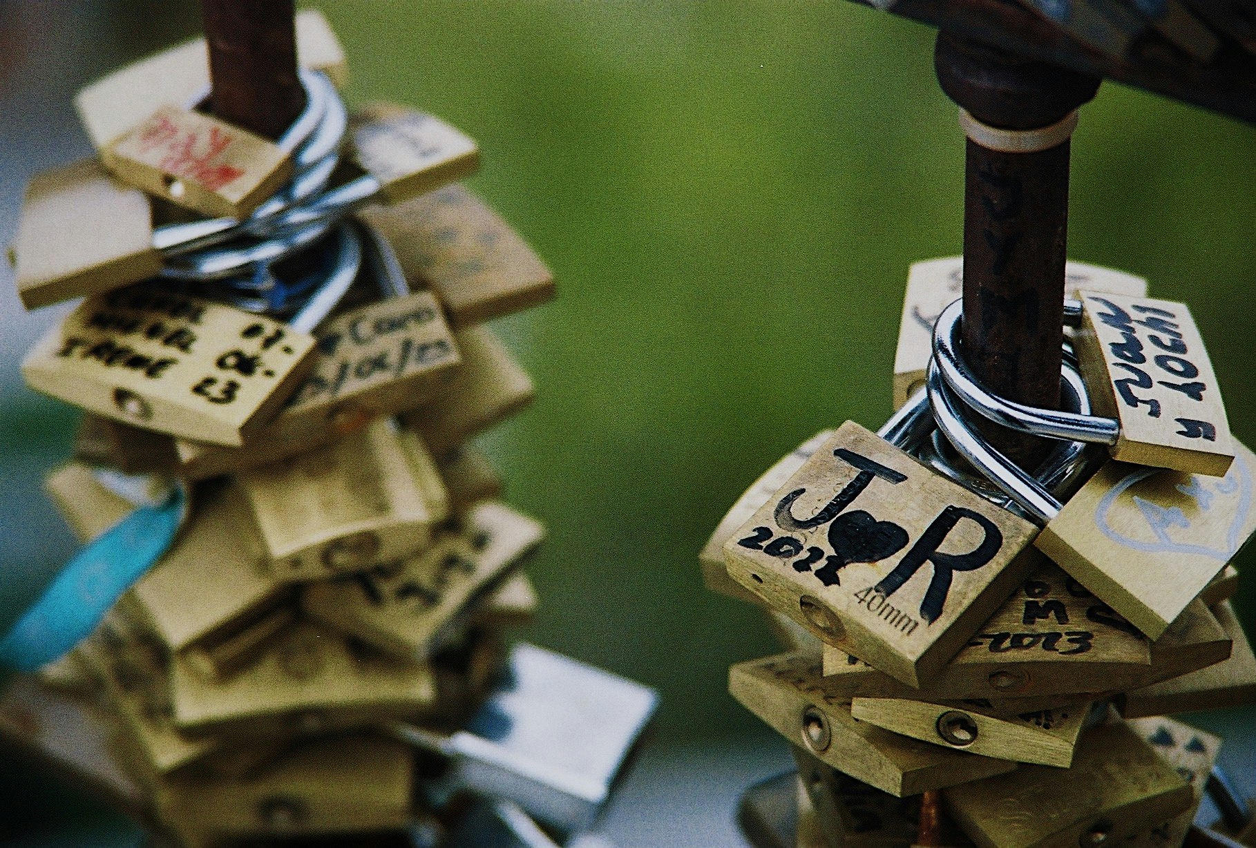 Close-up of wooden padlocks and message tags on a green background