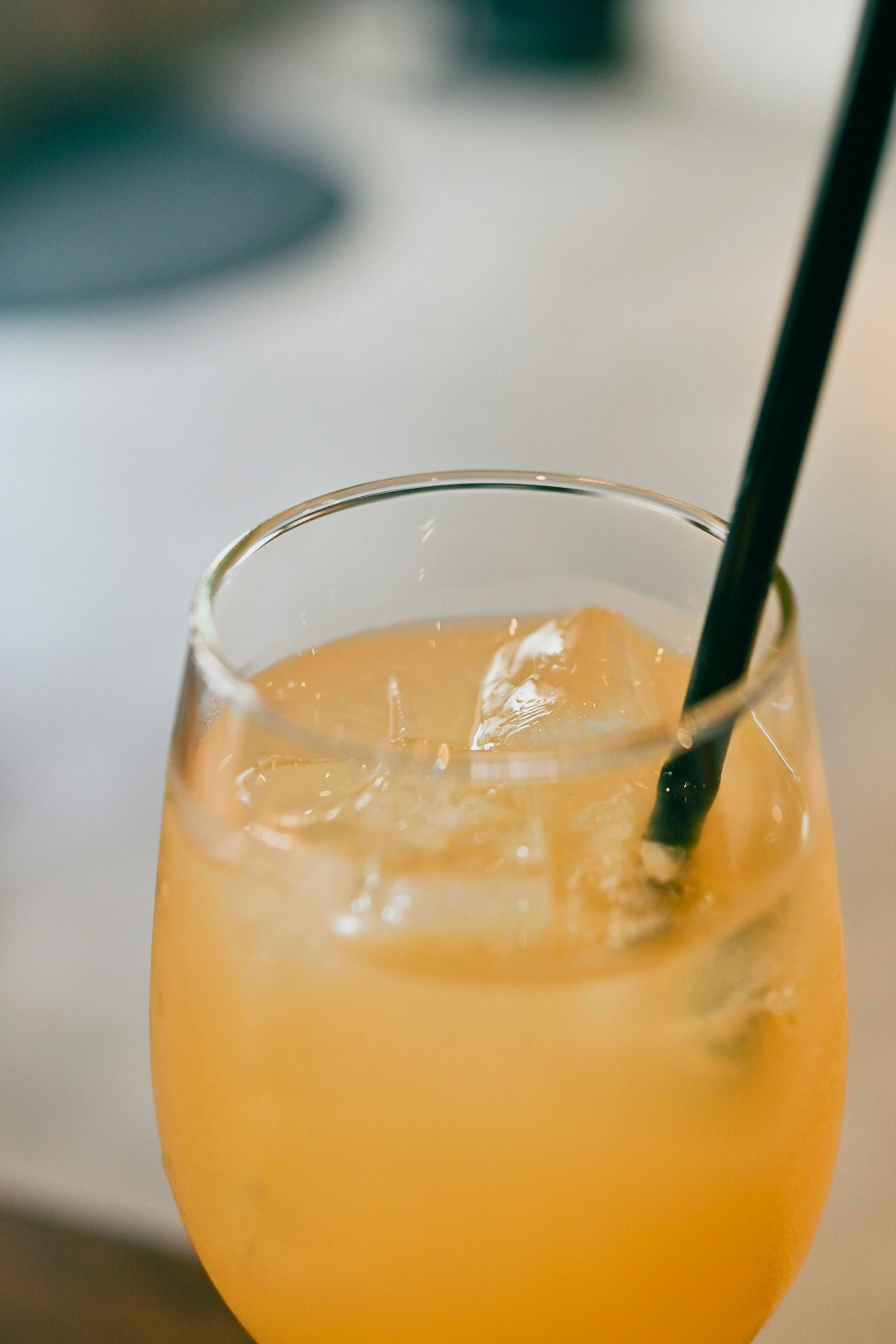 Un verre de boisson orange avec des glaçons et une paille