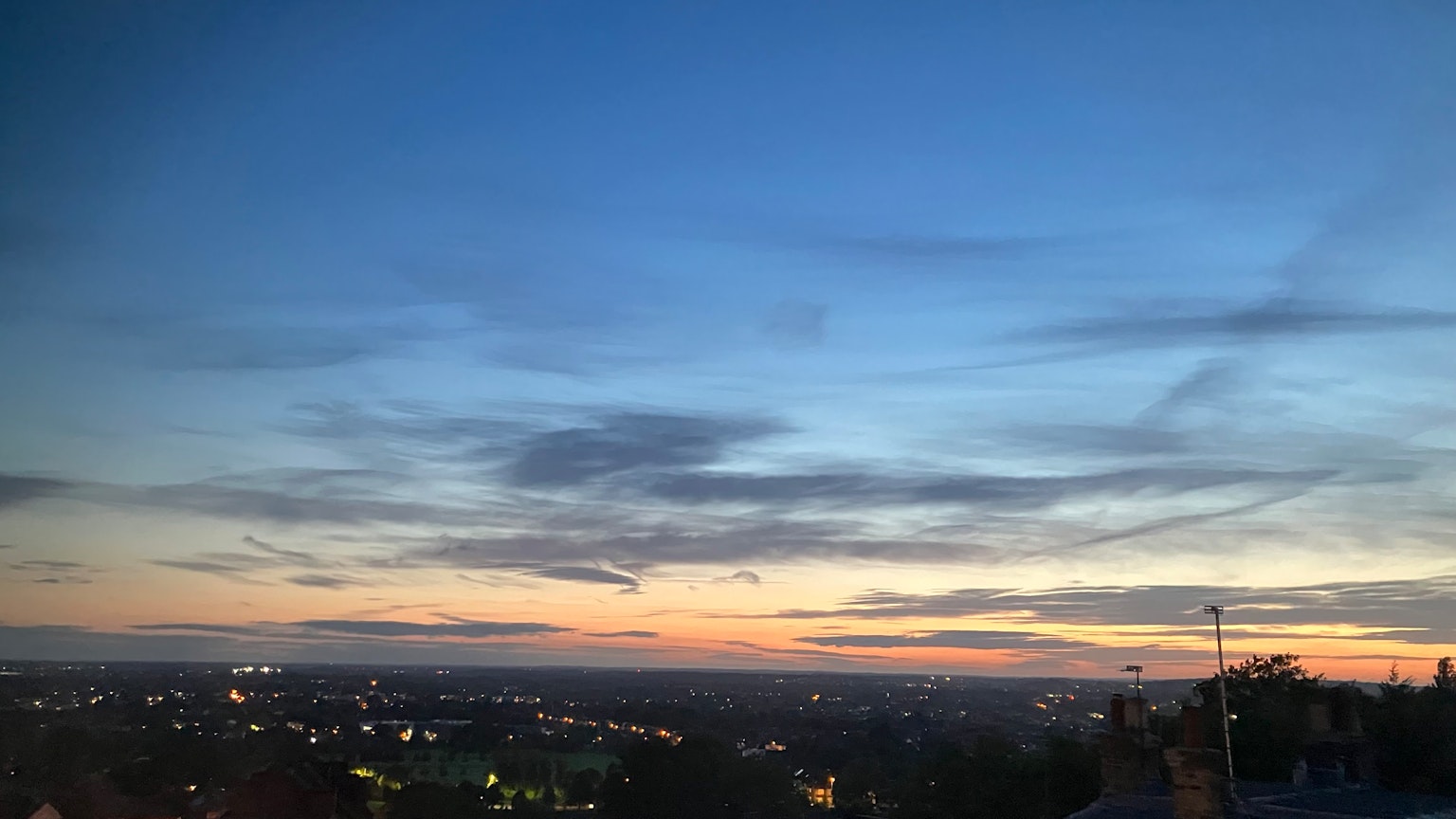 Hermoso paisaje de atardecer con cielo naranja y azul brillante luces de la ciudad dispersas