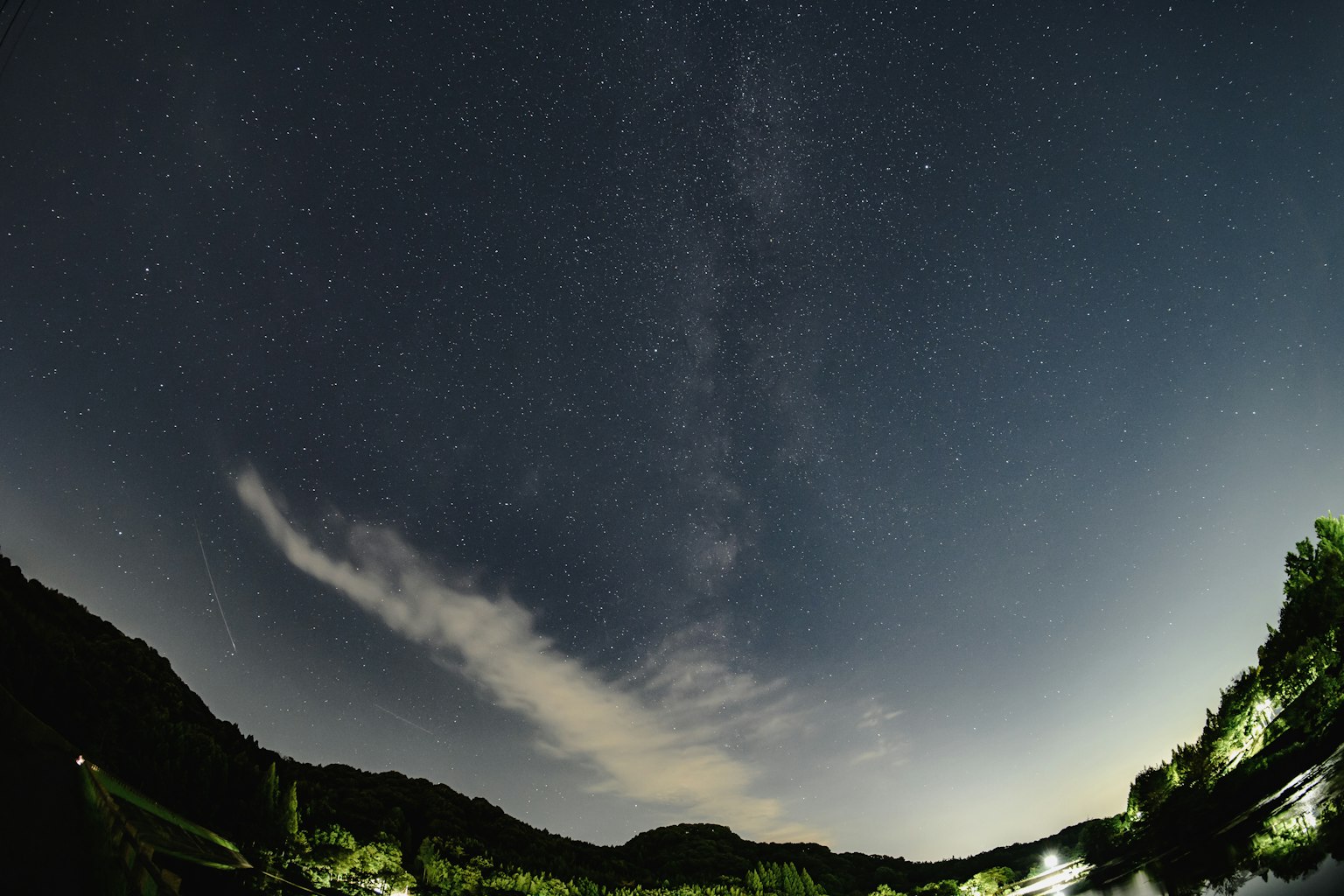 Cielo notturno con stelle e nuvole sopra le montagne