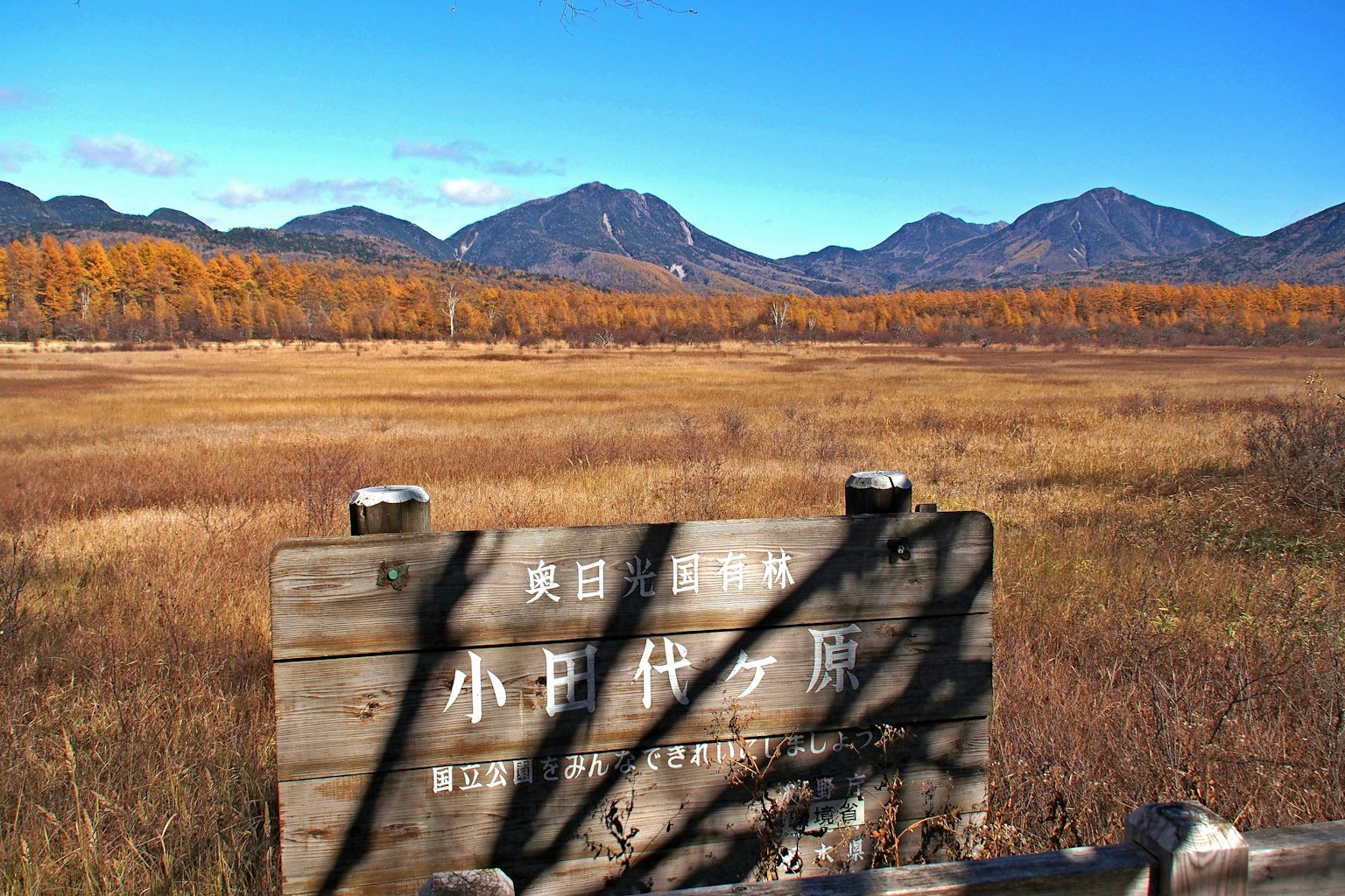 Scenic view of mountains and autumn grassland with a sign