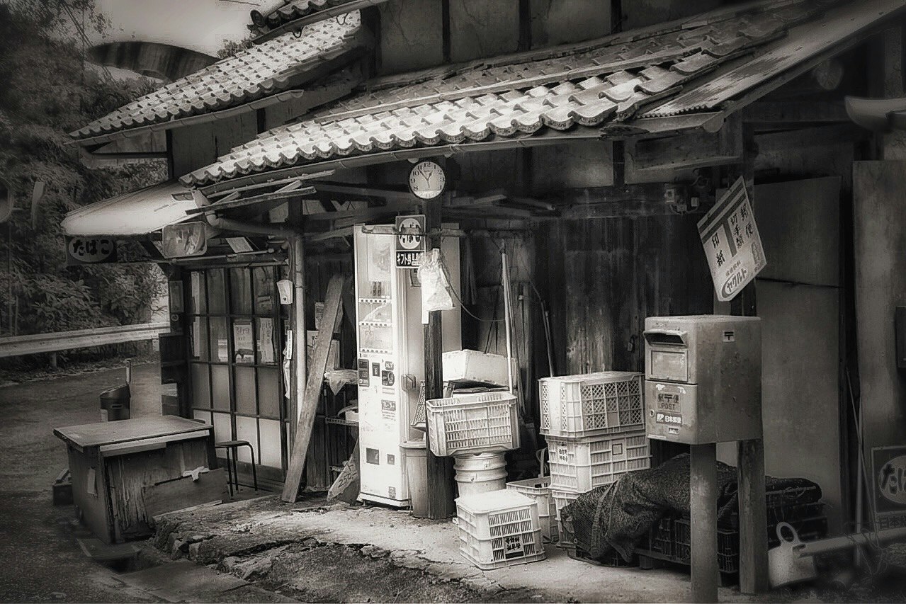 古い商店の軒先に並ぶ棚と箱のある路地