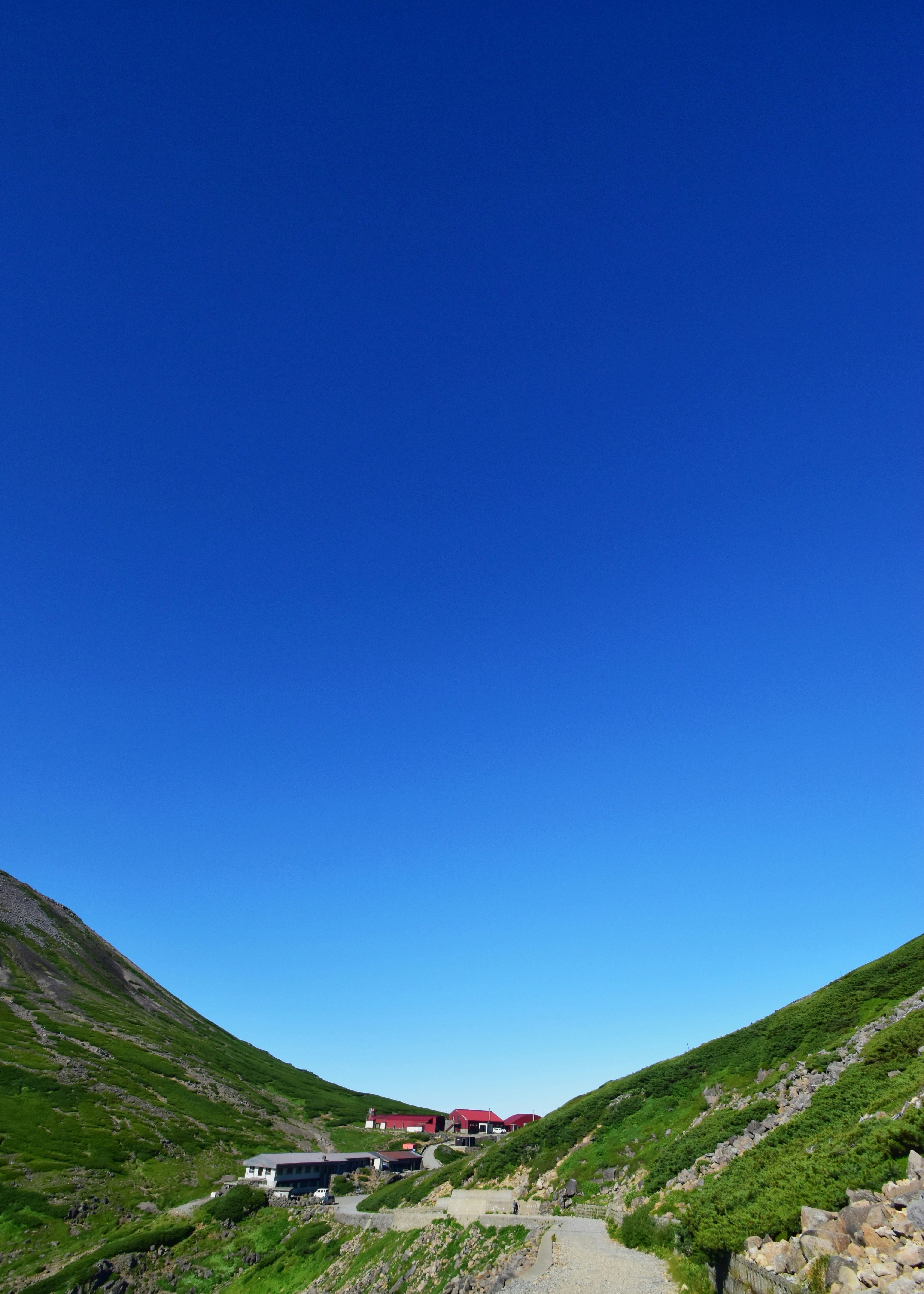 乗鞍岳の稜線と青空の下にある肩の小屋周辺の登山道と建物群
