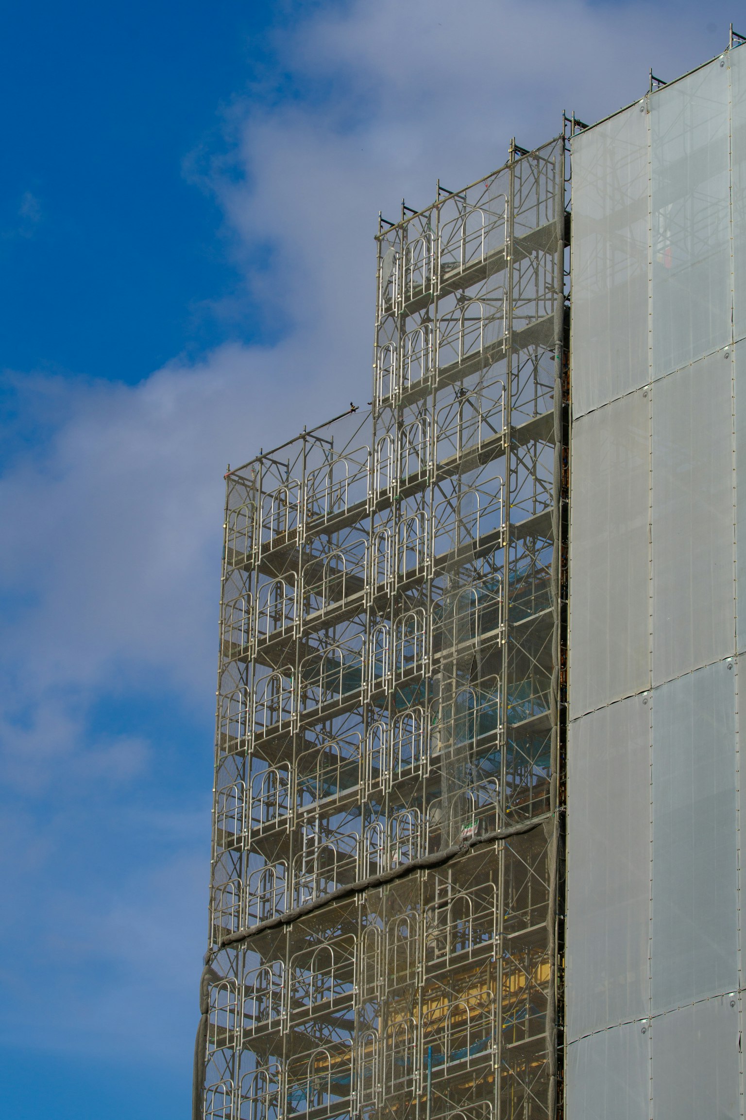 Ponteggio su un edificio con un muro trasparente contro un cielo blu