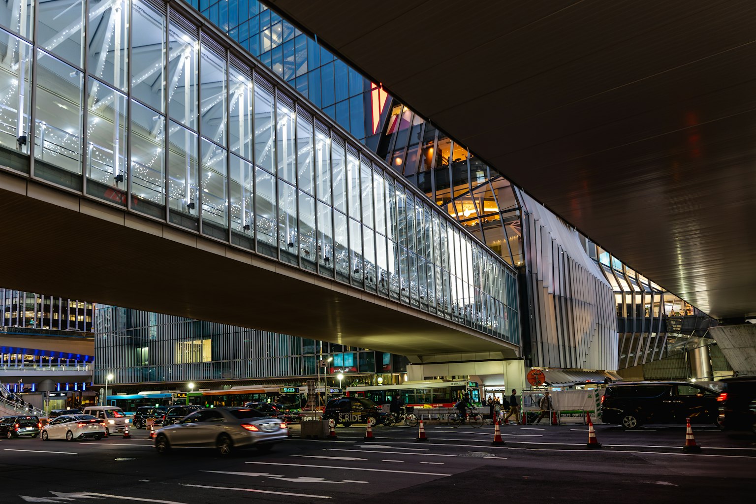 Night cityscape featuring a glass pedestrian bridge and vehicles
