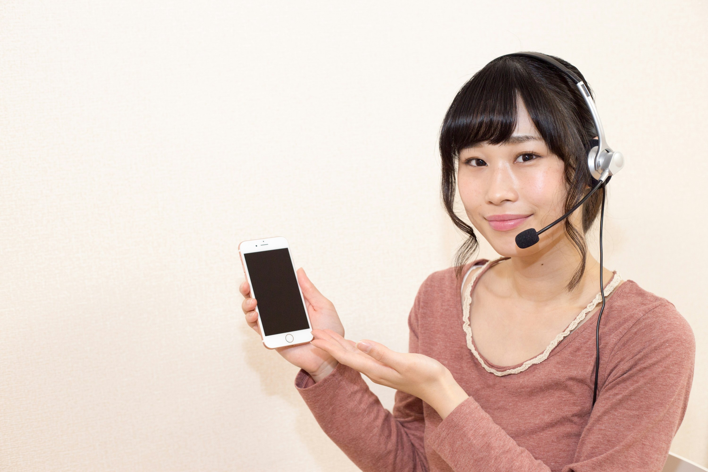 Frau mit Headset hält ein Smartphone