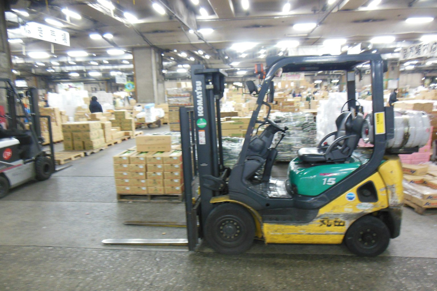 รถยกในโกดังพร้อมกล่องที่ซ้อนกันอยู่ด้านหลัง