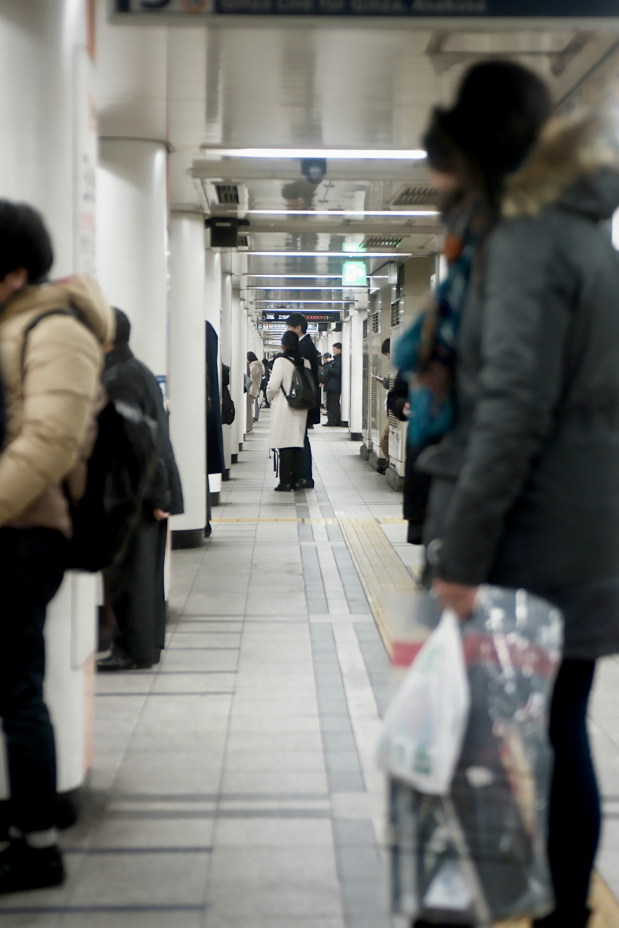 people with luggage in a station corridor