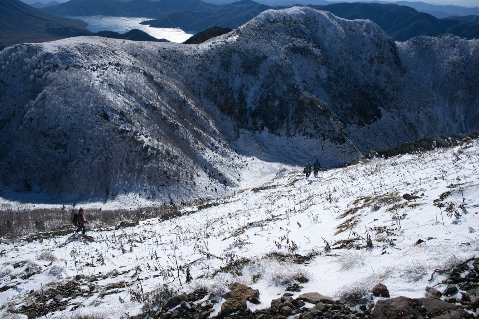 Escursionisti che salgono un pendio montuoso coperto di neve
