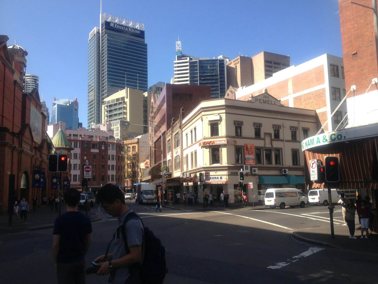 Straßenansicht von Sydney mit modernen Wolkenkratzern und historischen Gebäuden unter blauem Himmel und Ampeln