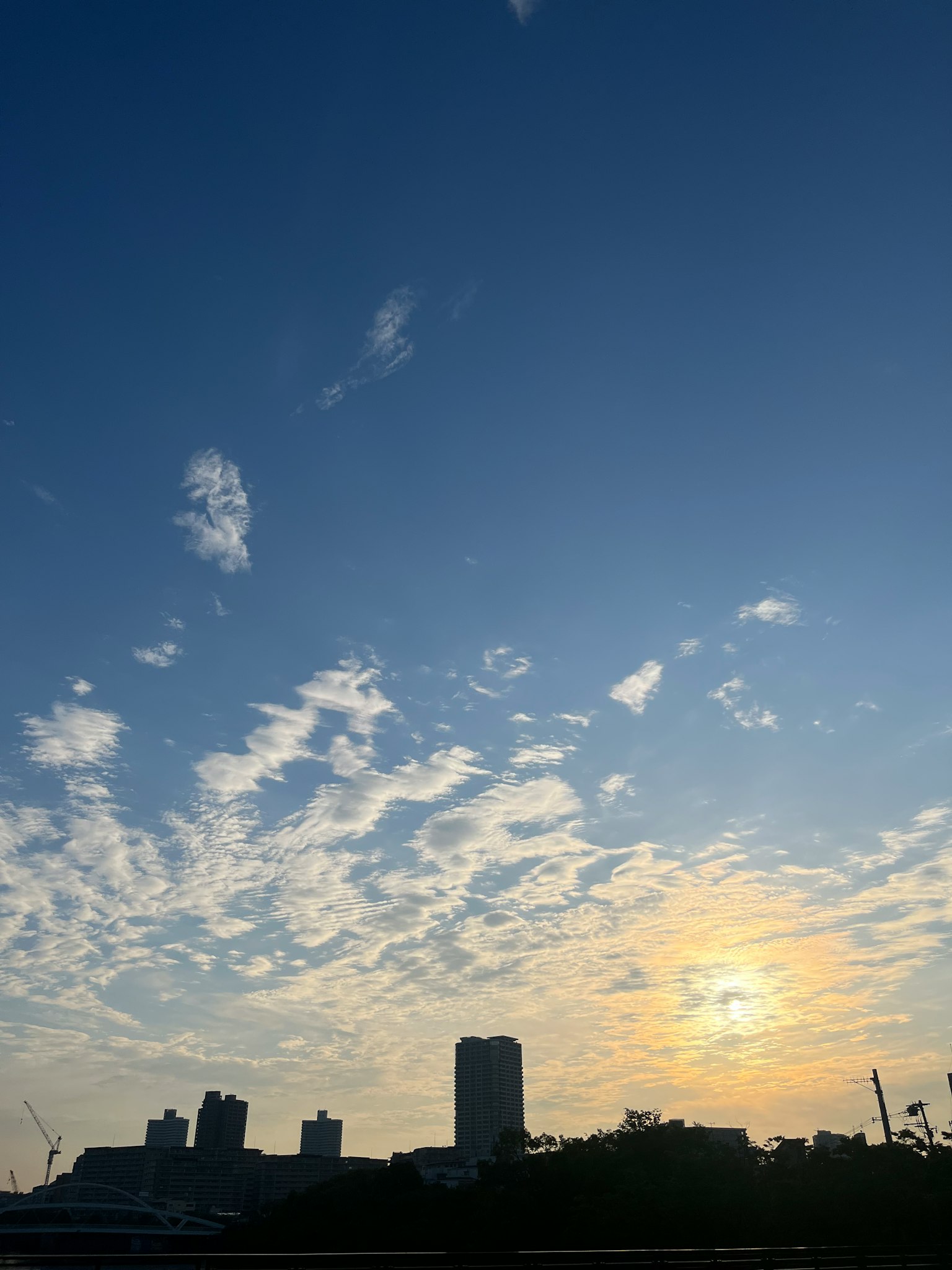 Silhouette bangunan di bawah langit biru dengan awan saat matahari terbenam