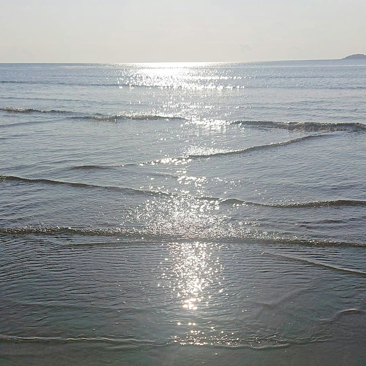 Pemandangan laut tenang dengan pantulan di gelombang
