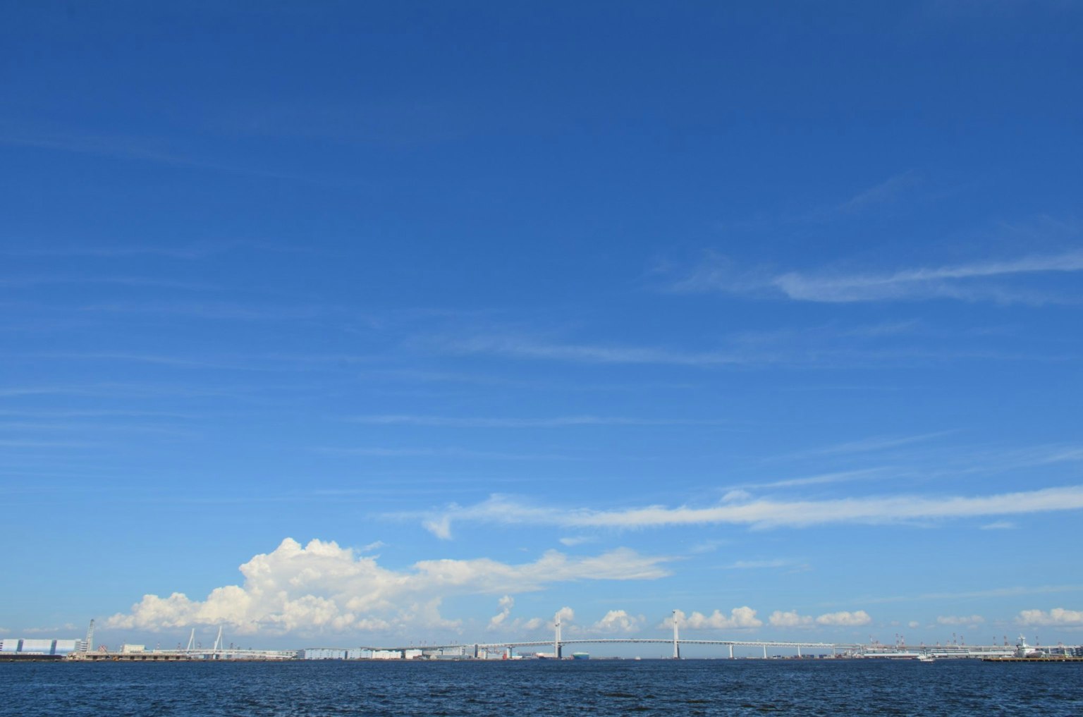 Vaste ciel bleu au-dessus de la mer calme avec des nuages blancs épars