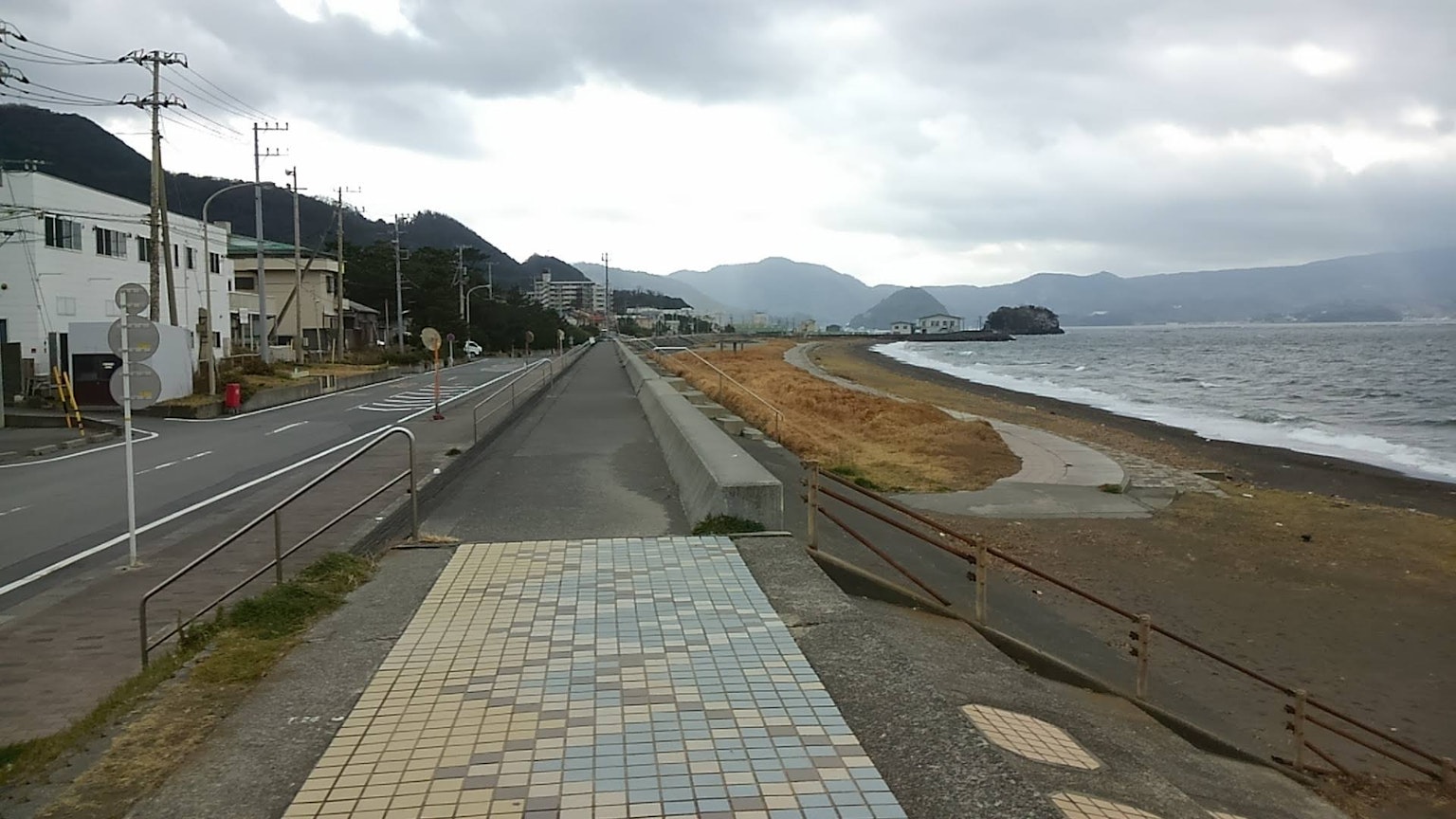 Jalan pesisir dengan langit mendung dan pemandangan pantai