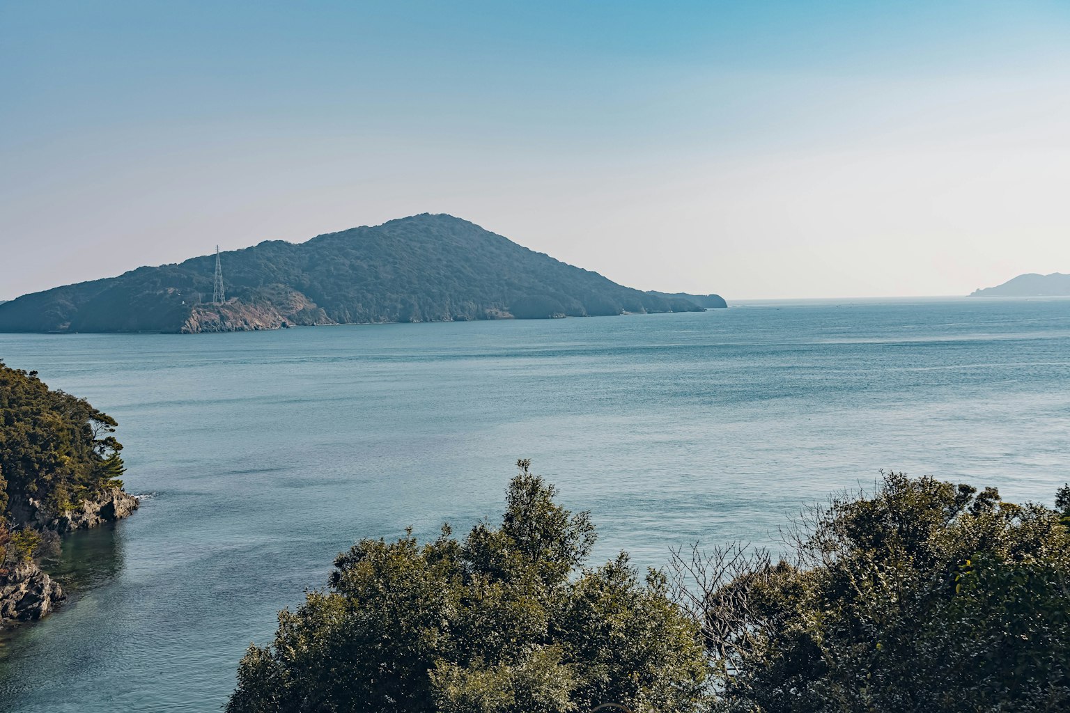 ทิวทัศน์ที่เงียบสงบของเกาะที่มีน้ำสงบและพืชสีเขียวล้อมรอบ