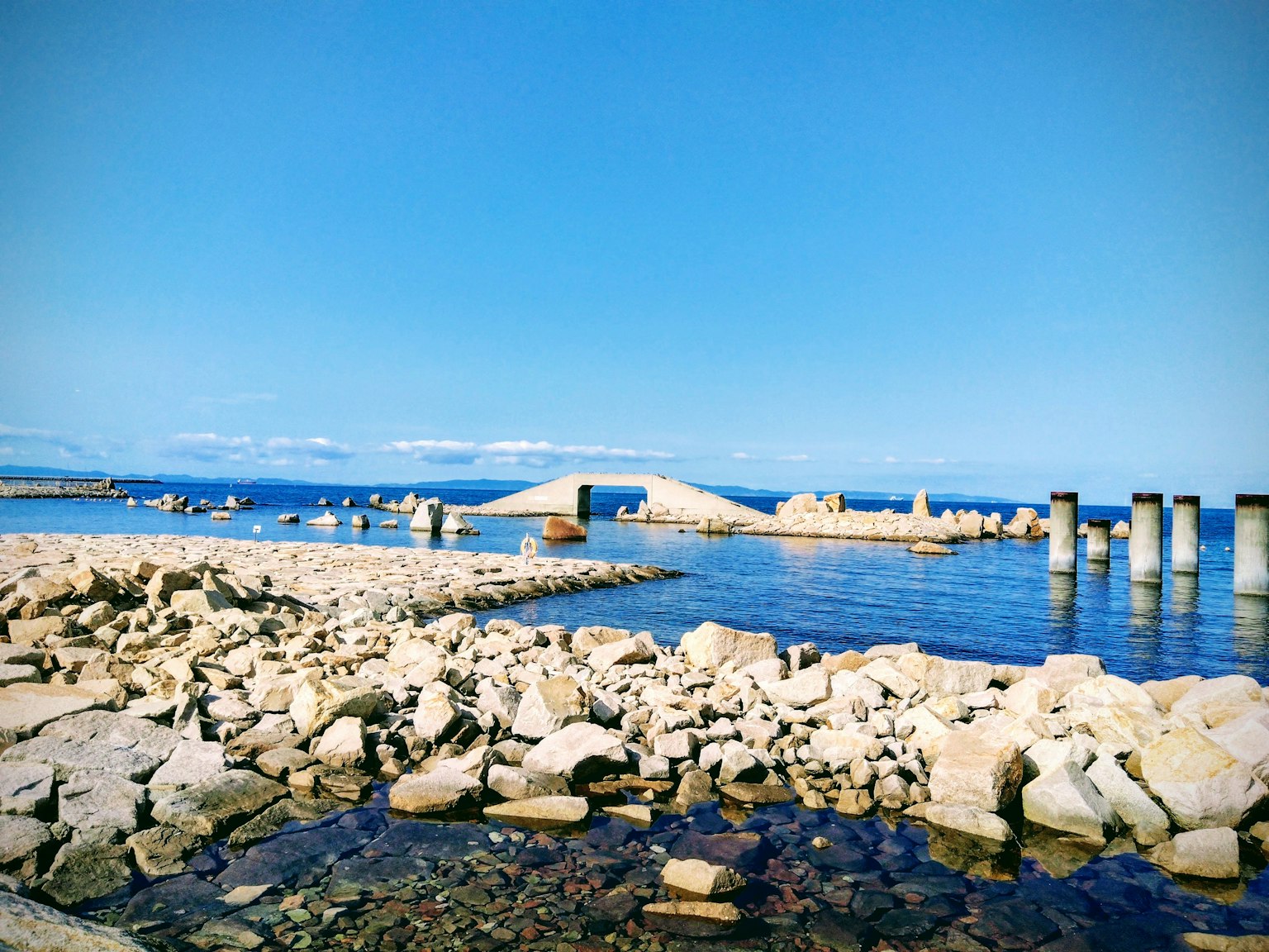 Scenic view of a stone bridge against a blue sky and water