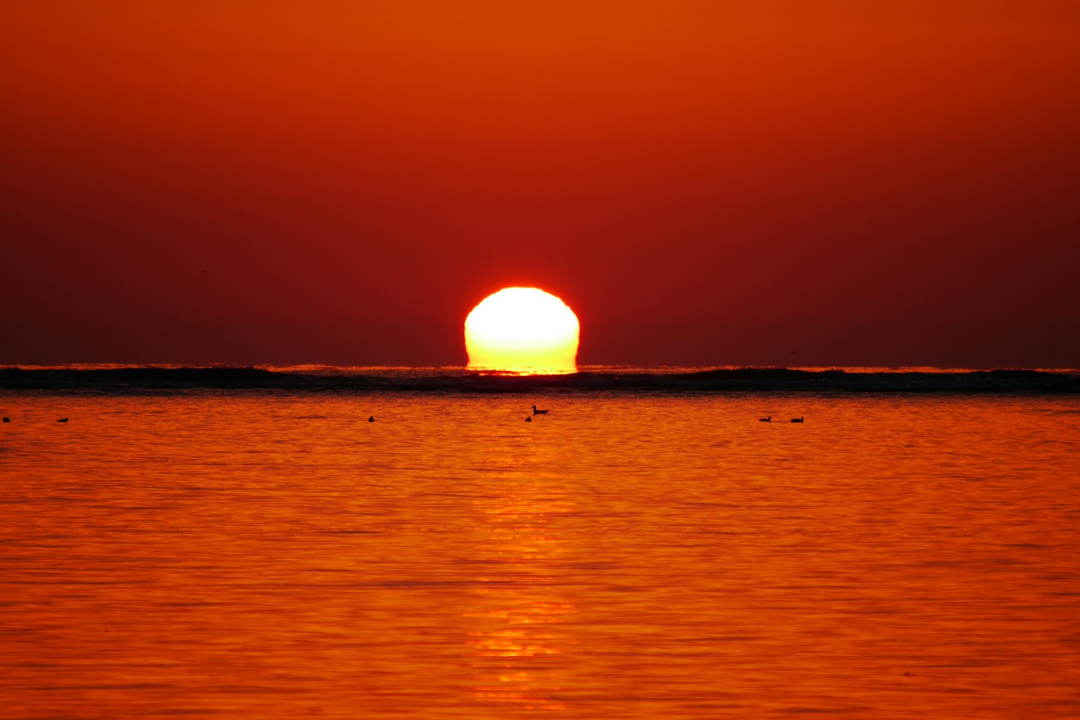 Un magnifique coucher de soleil sur l'océan avec un ciel orange et des reflets sur l'eau