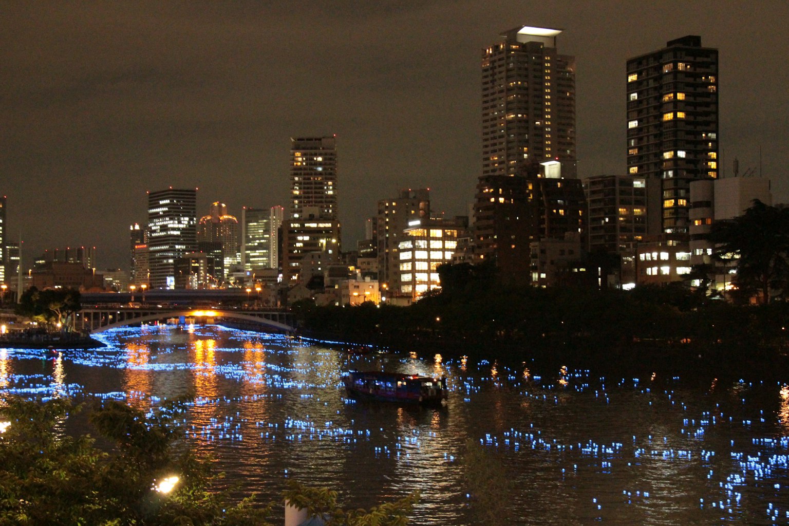 Panorama urbano notturno con luci blu riflesse sul fiume