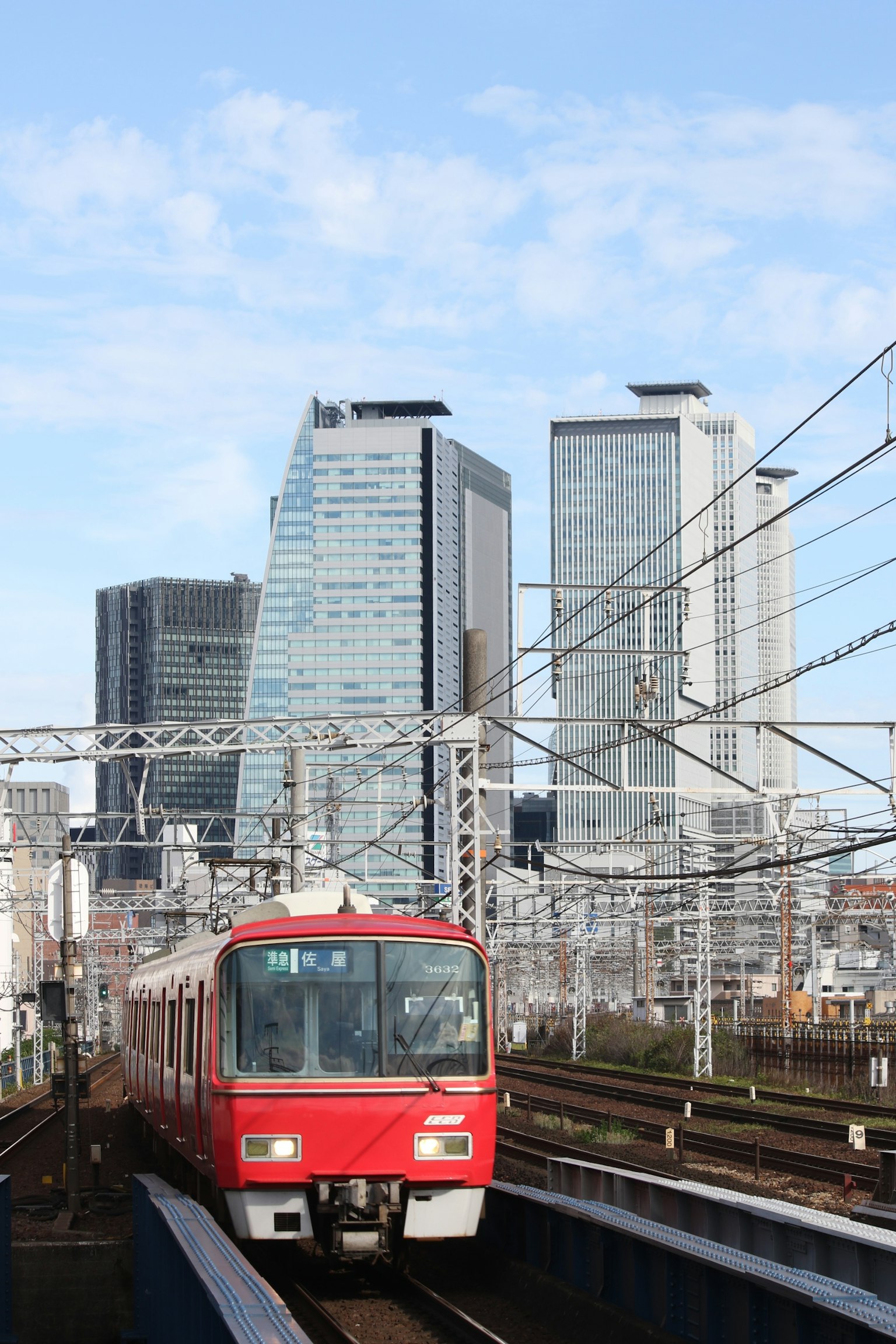 Red train running between tall buildings