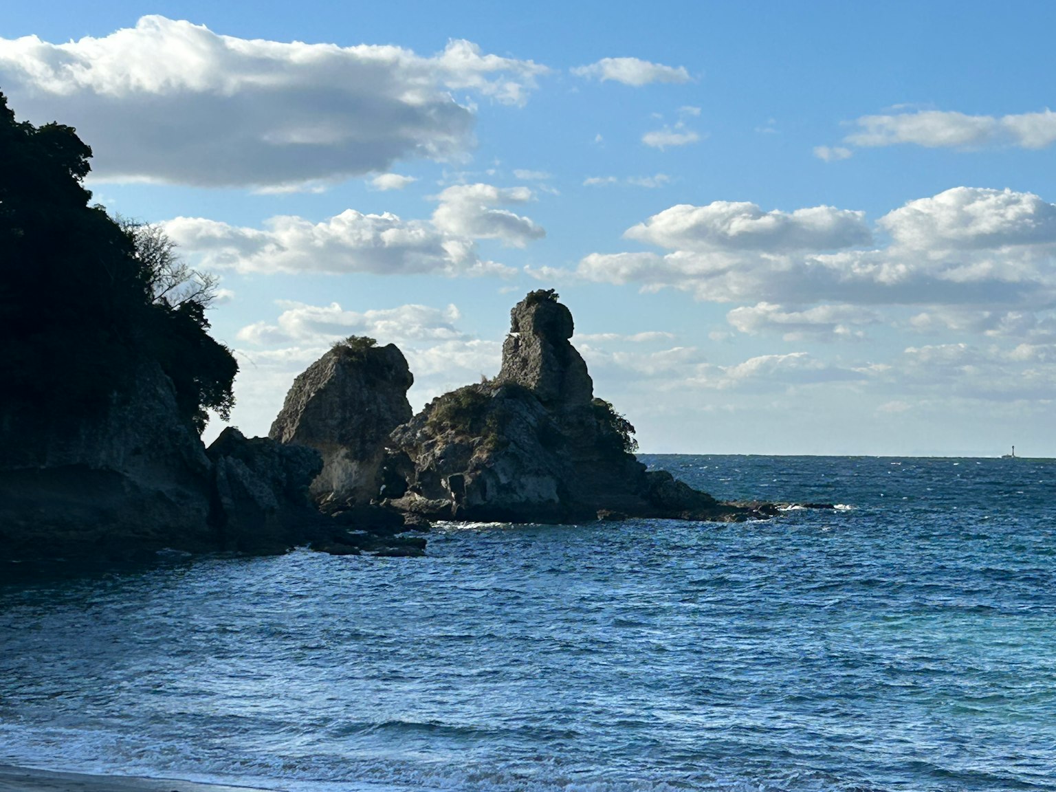 Felsen, die aus dem blauen Meer unter weißen Wolken ragen