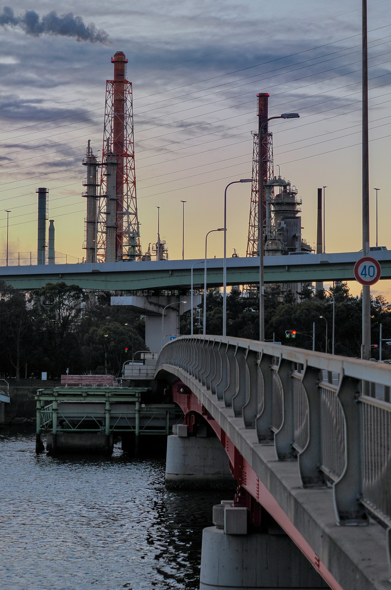 Industrial plant and bridge scene at dusk with colorful sky