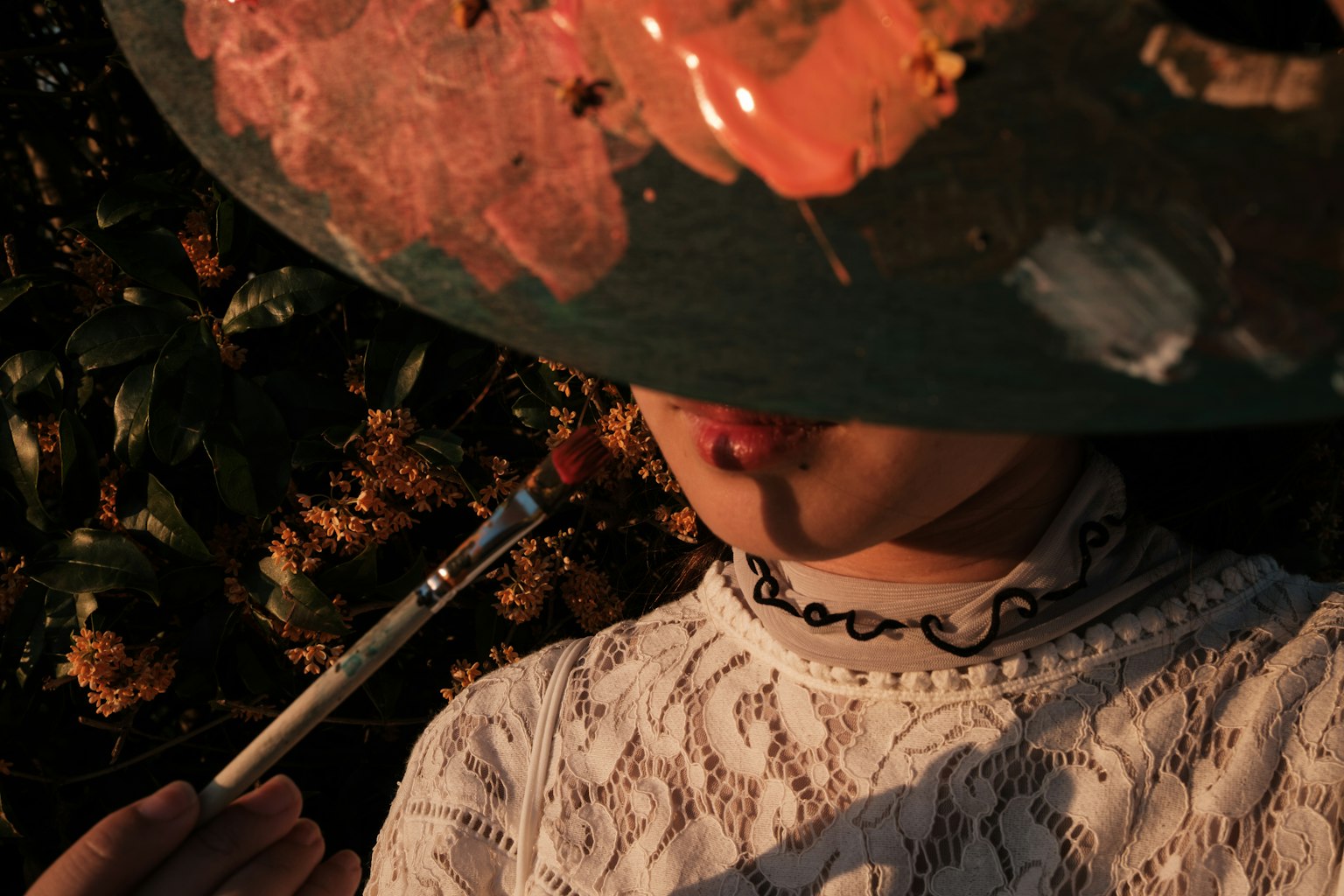 Seorang wanita memegang palet cat besar dengan kuas di mulutnya