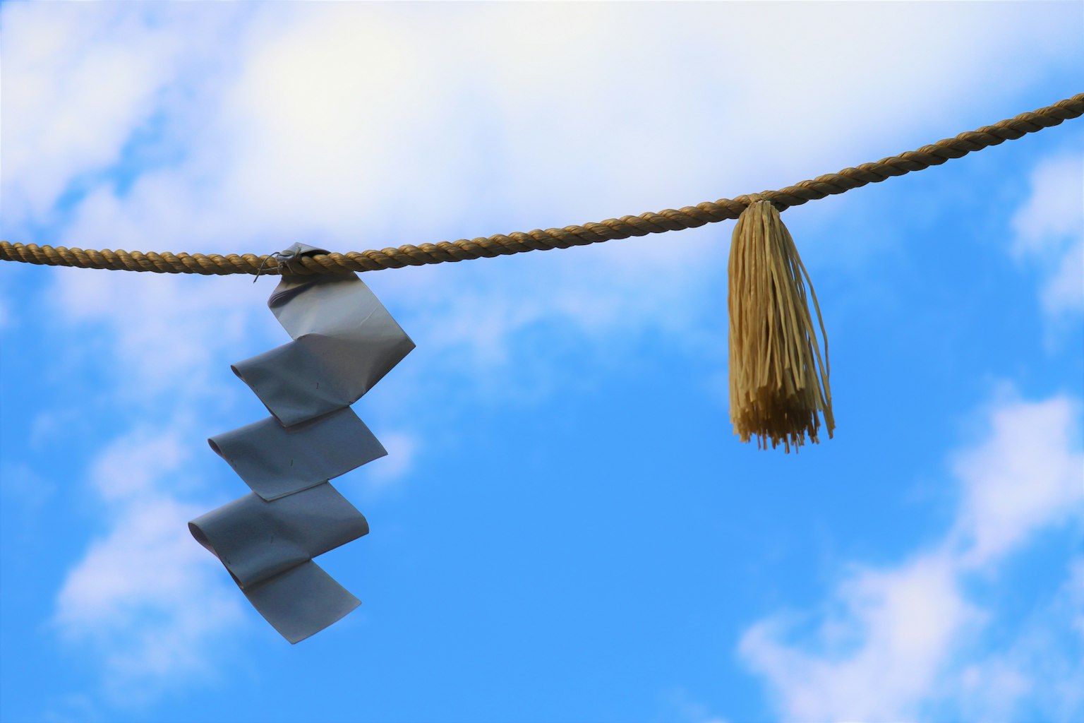 Decorative paper and tassel hanging against a blue sky