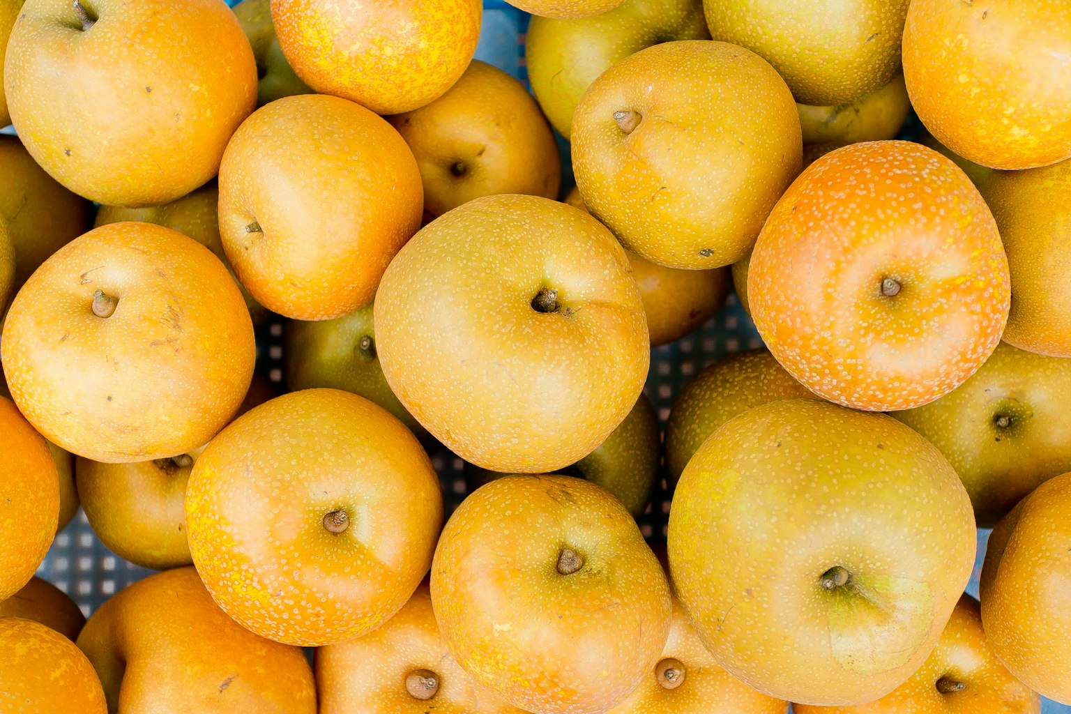 Un gros plan de nombreuses pommes jaune-orange empilées