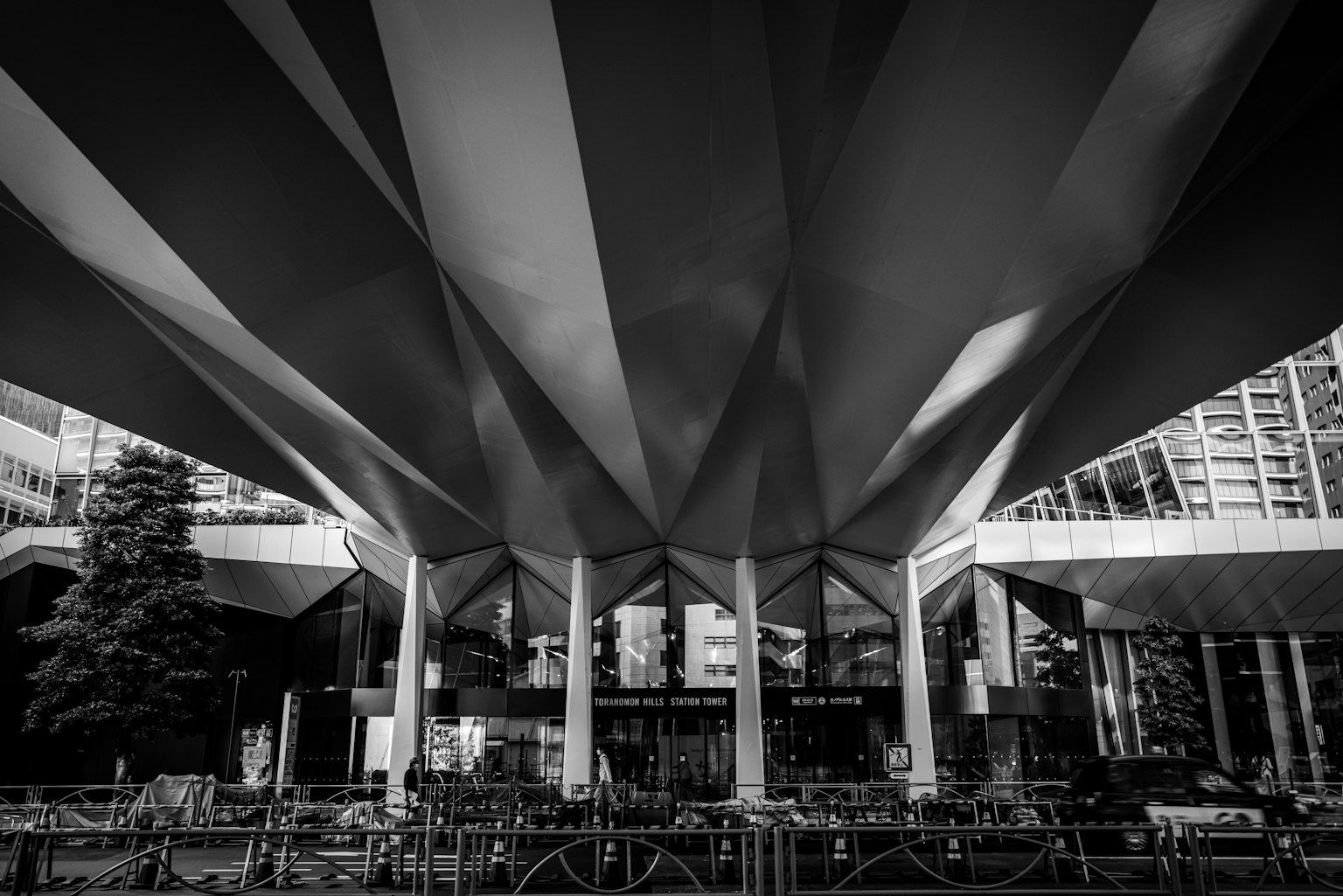 Schwarzweißfoto von unten unter einer modernen Architektur mit großem Dachdesign und Säulen