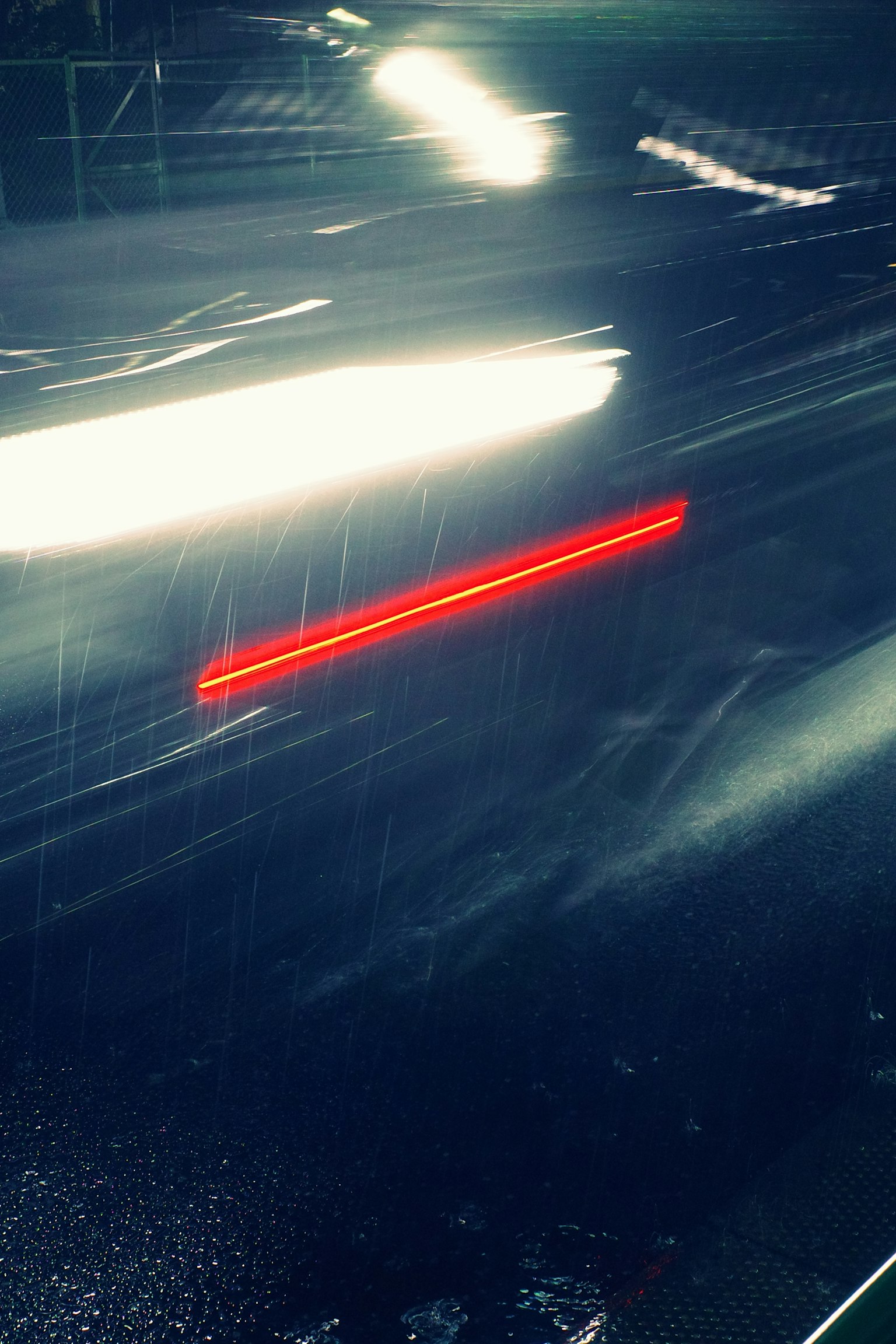 雨の中で流れる車のテールランプとヘッドライトの光