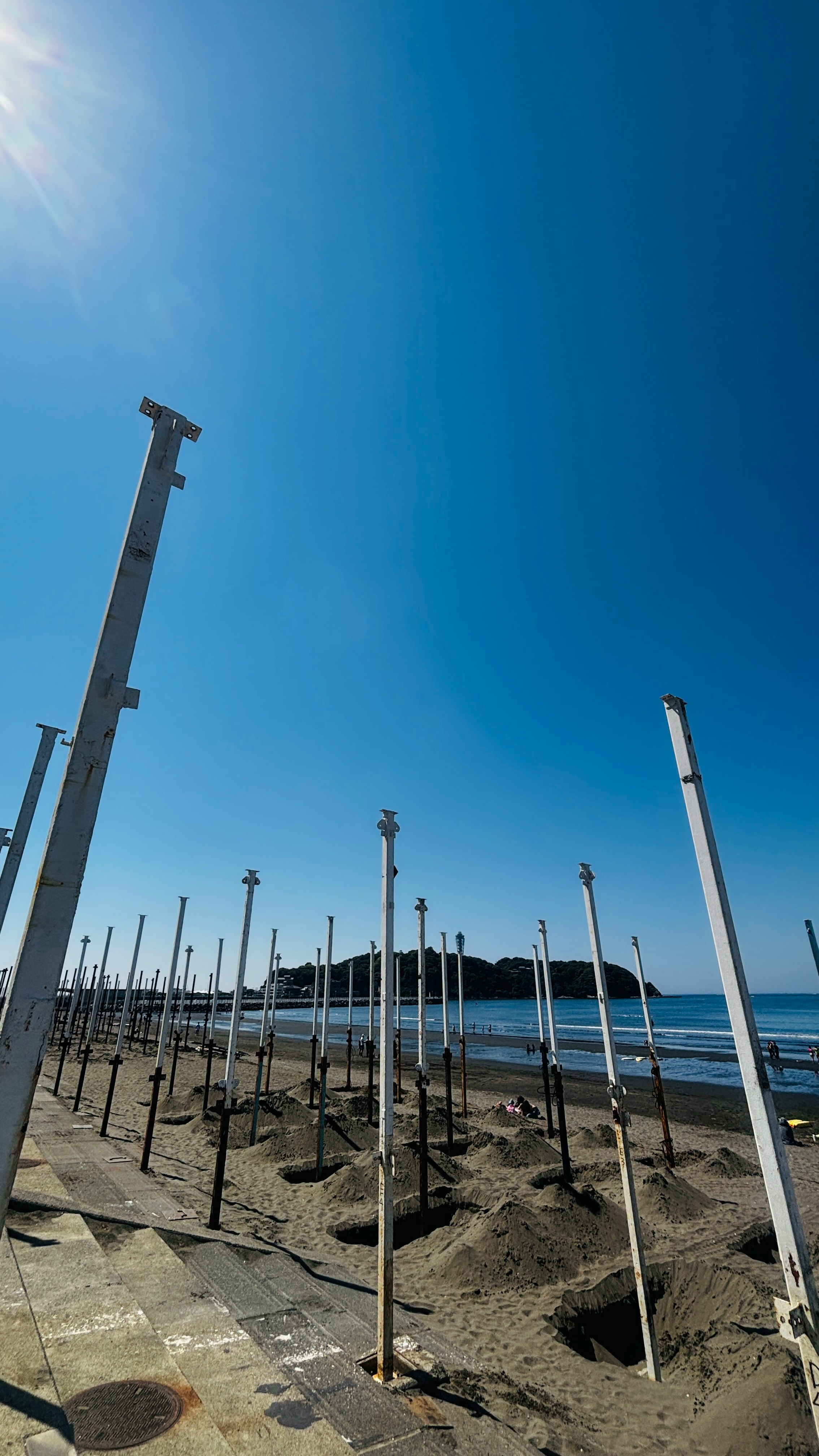 青空の下、海辺の並ぶ支柱と砂地