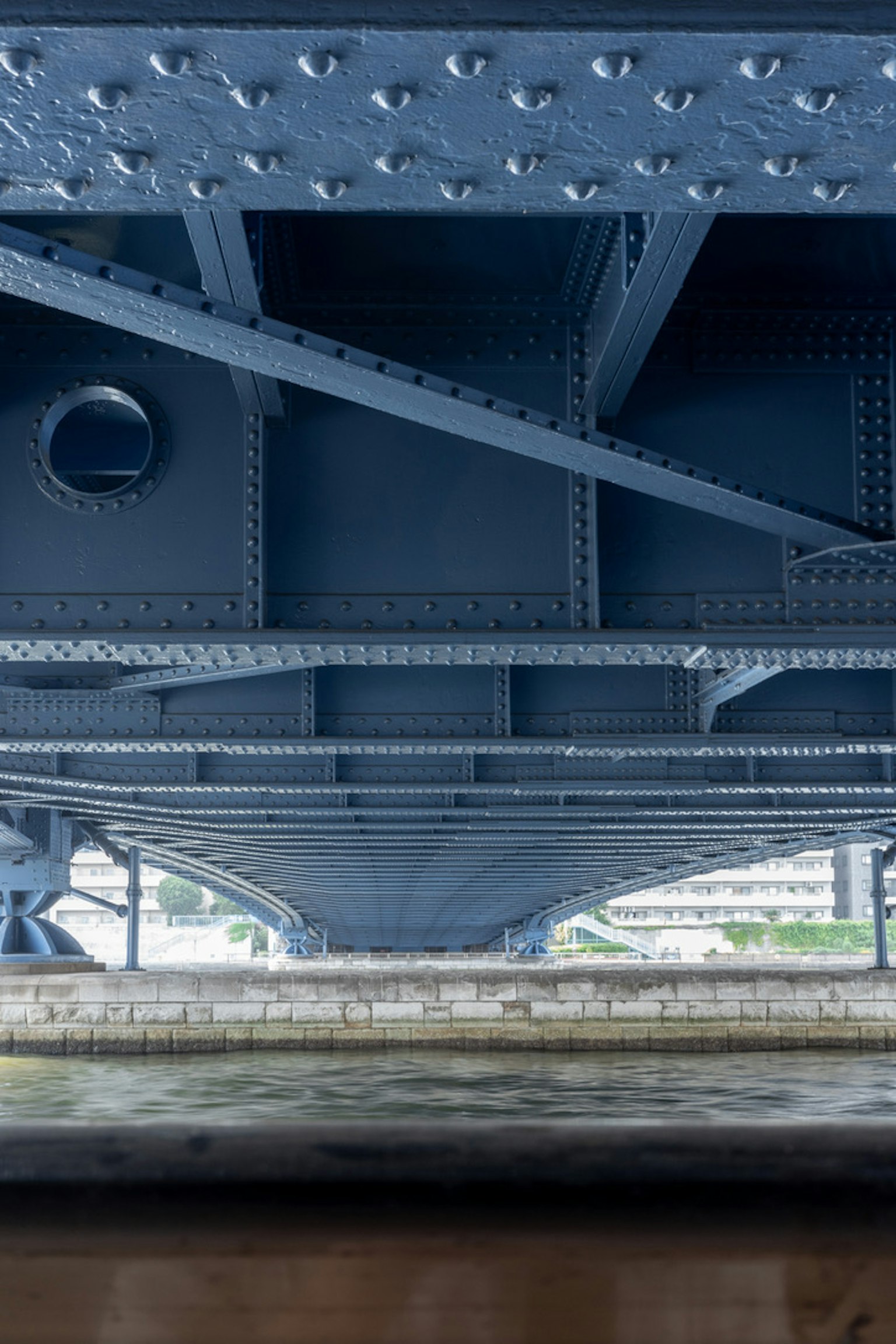 Structural details of a blue bridge from underneath with iron beams