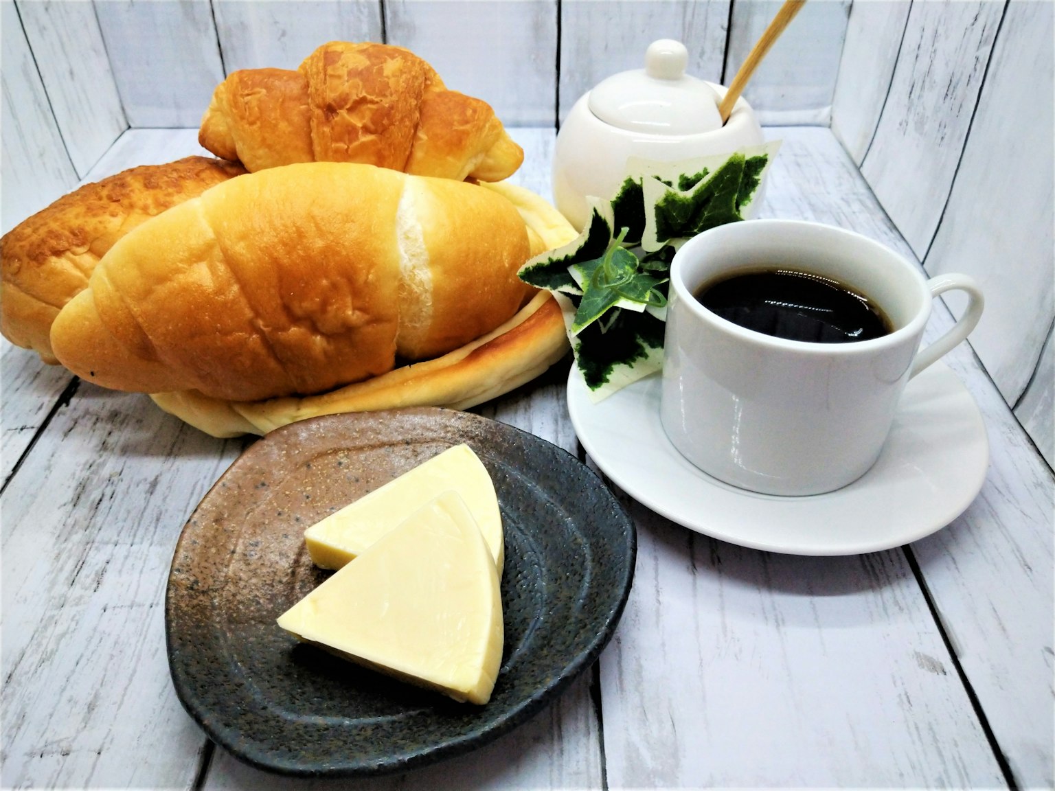 아침 식사 세팅 다양한 빵과 커피 버터와 샐러드 잎이 포함되어 있음