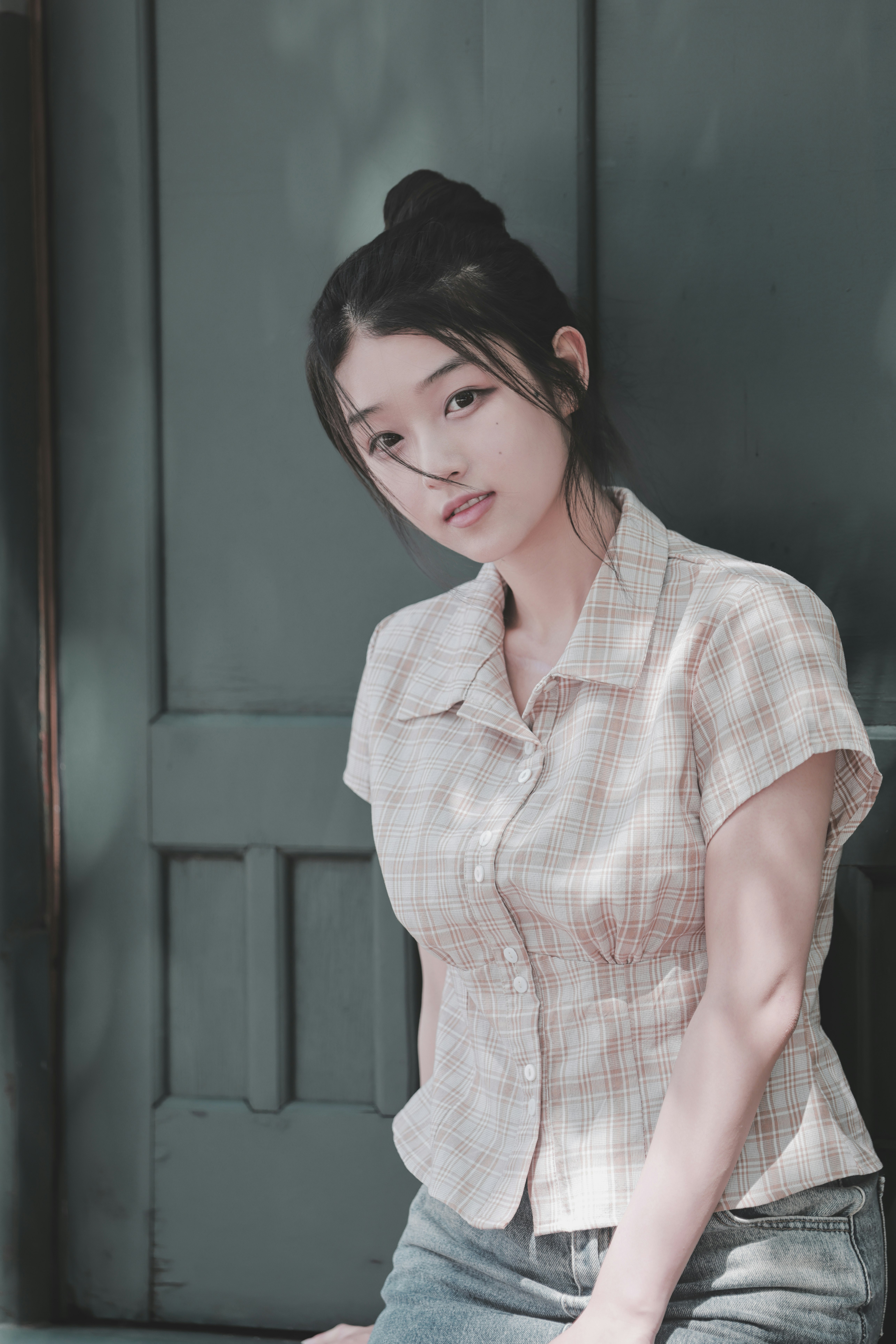 woman in a checkered shirt standing by a wall