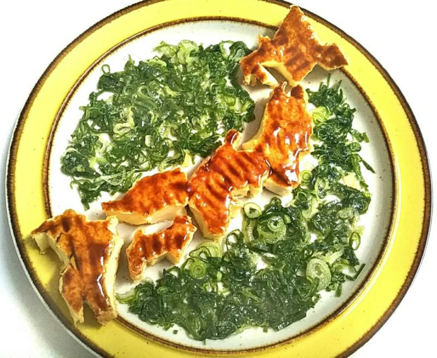 A plate with green vegetables and grilled fish arranged artistically