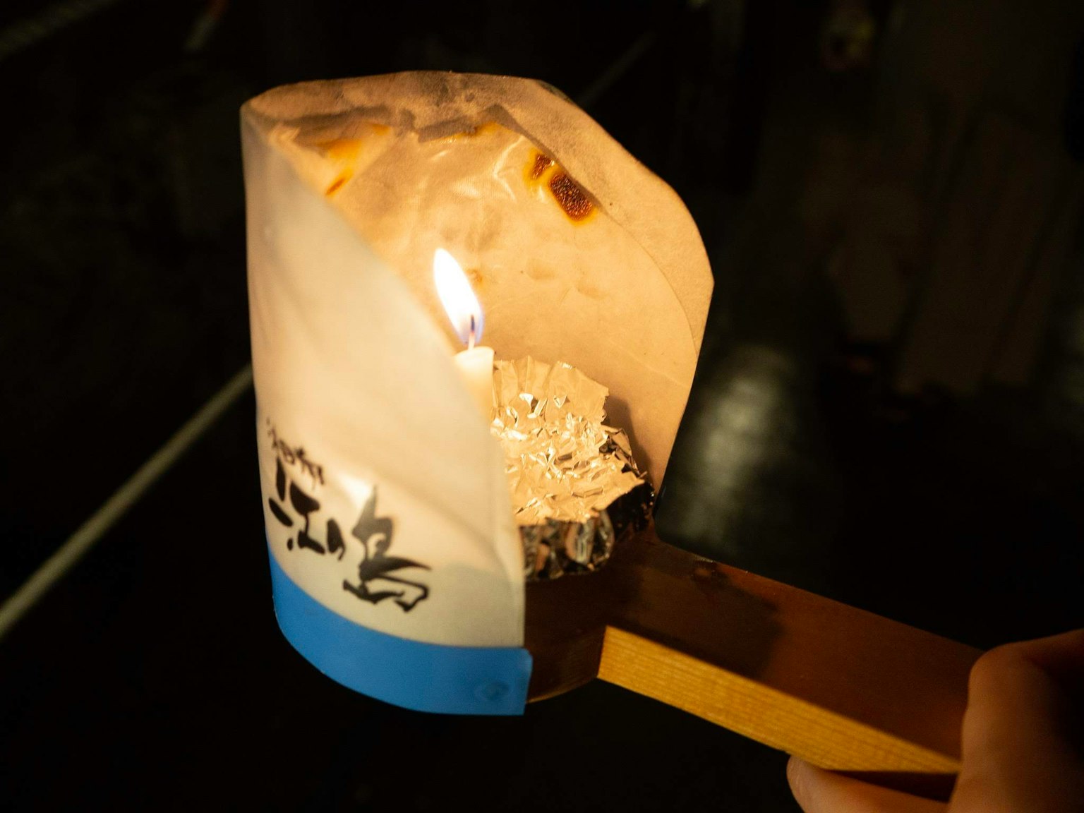 Hand hält eine traditionelle japanische Kerze mit Flamme