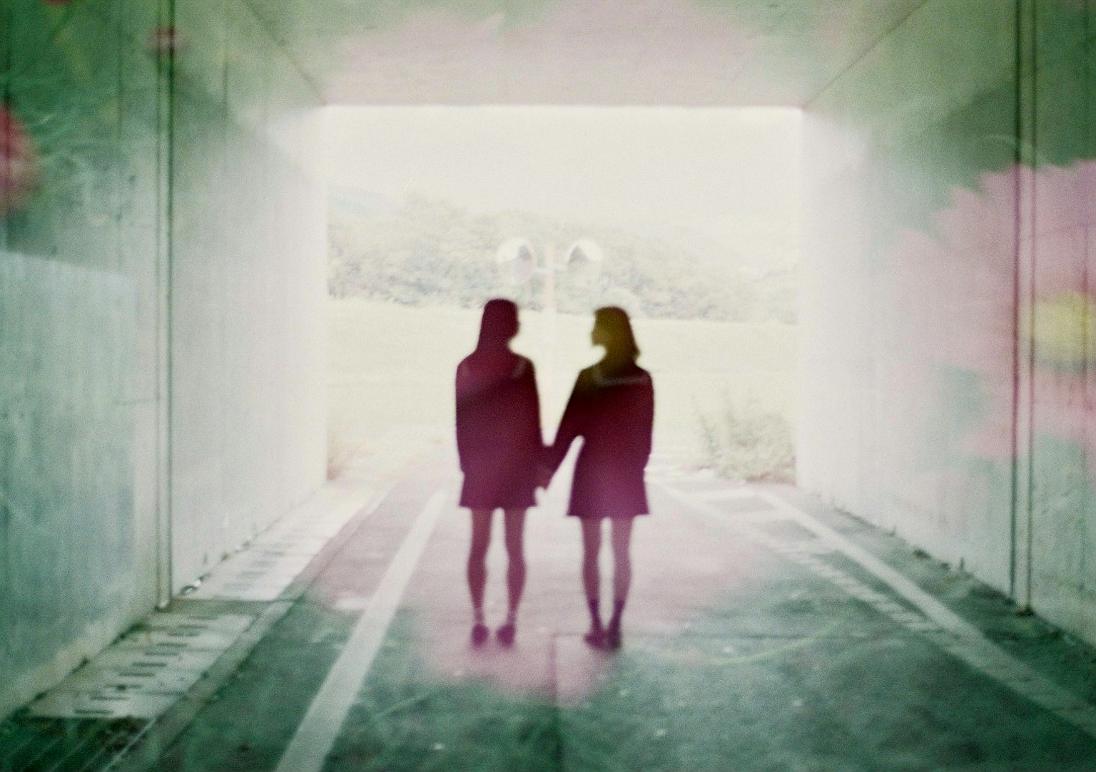 Silhouette di due donne che si tengono per mano in un tunnel