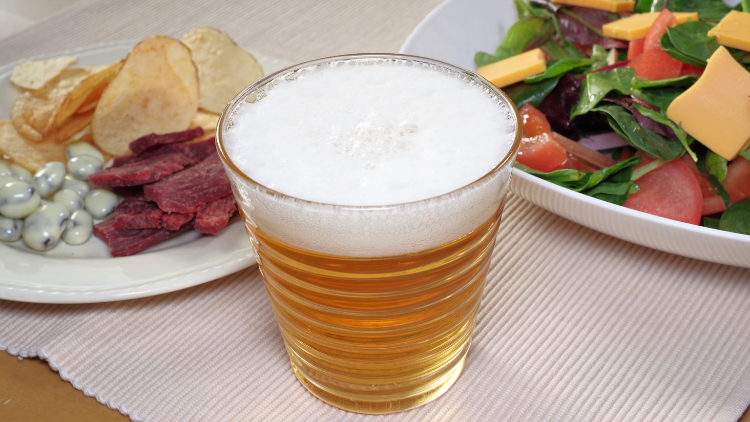 Un verre de bière avec une assiette de collations et une salade fraîche