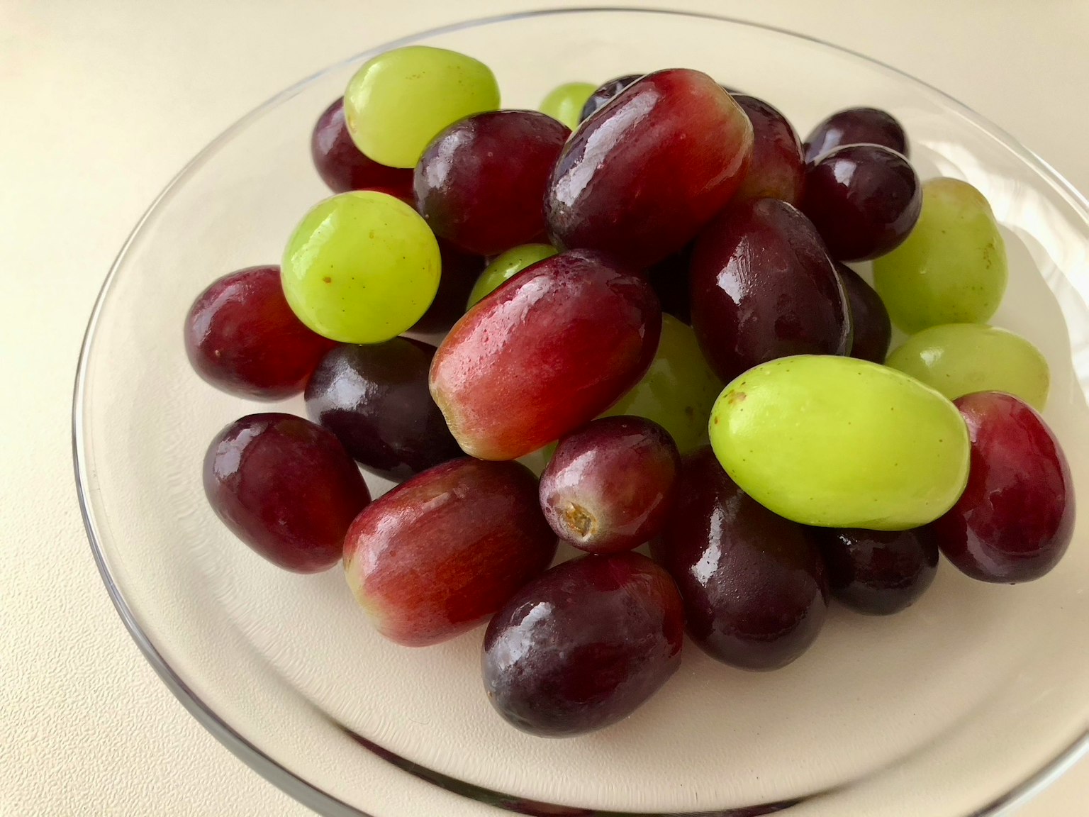 A mix of red and green grapes on a white plate