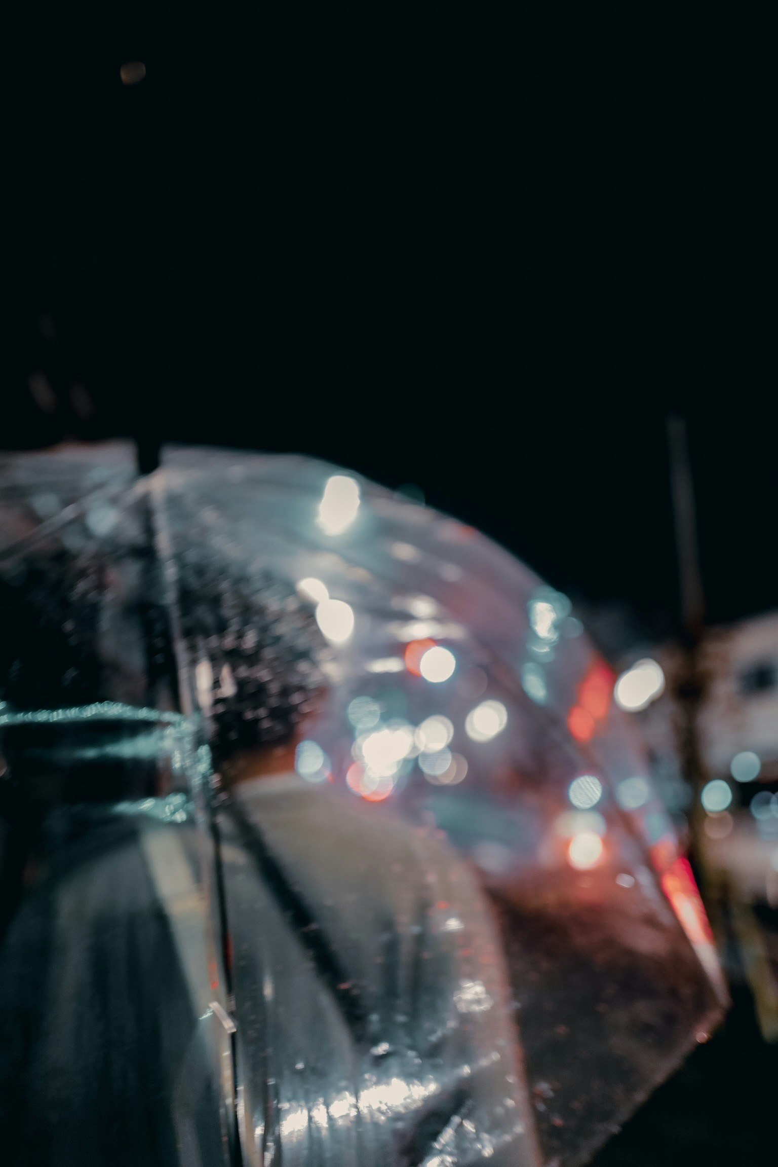 透明雨伞的特写，反射夜晚城市的灯光