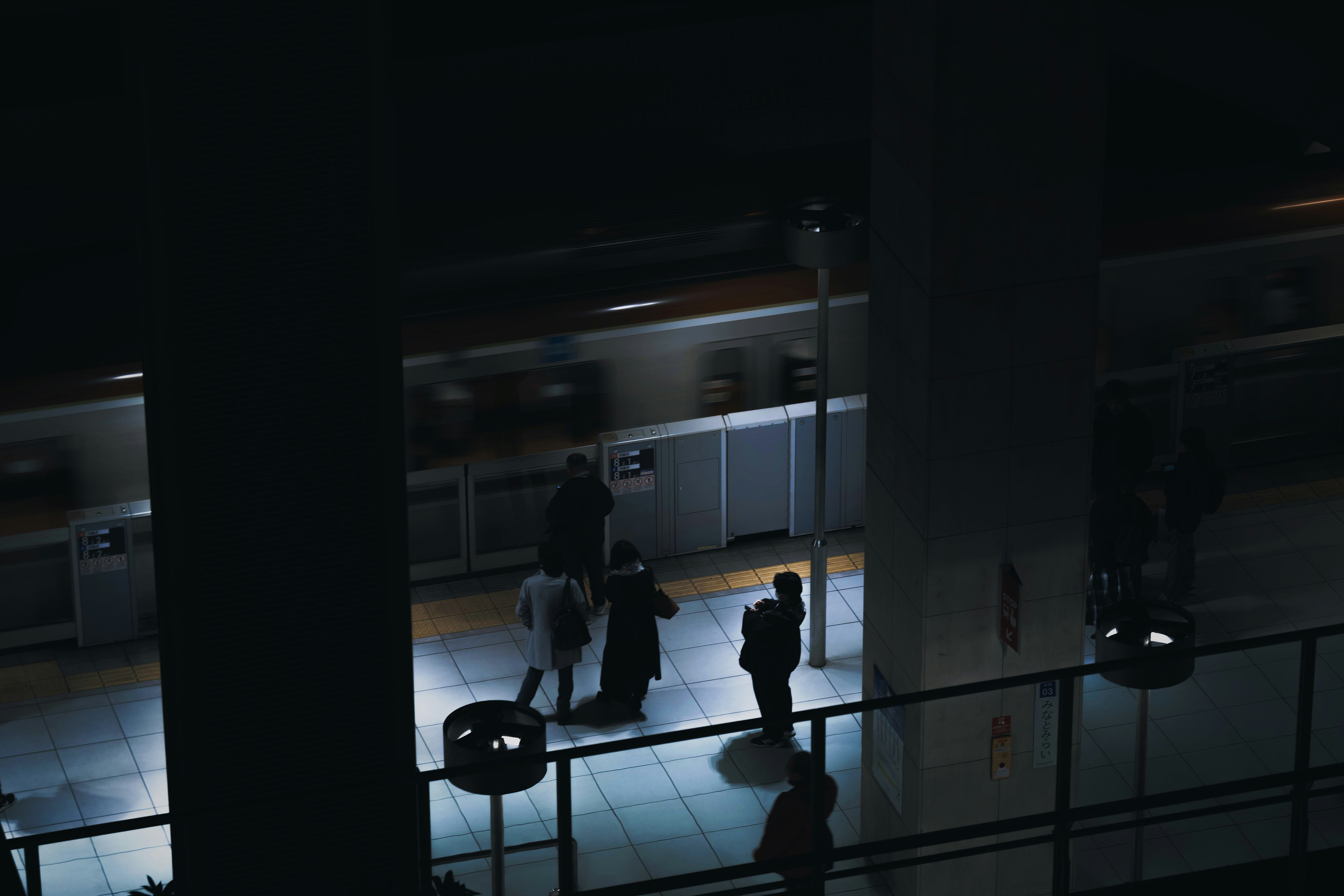 夜の屋内廊下で人影が行き交う駅のような空間