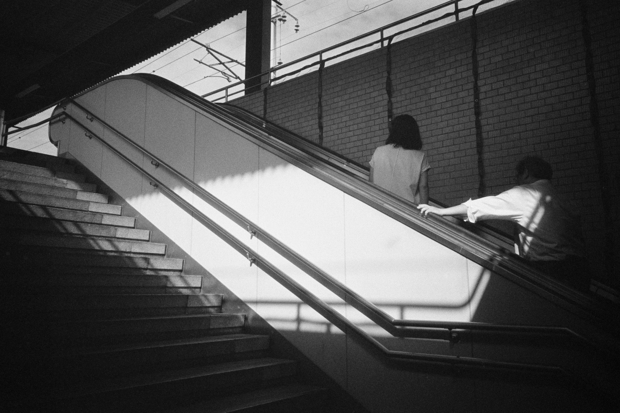 passaggio in bianco e nero con persone che camminano lungo le ringhiere delle scale